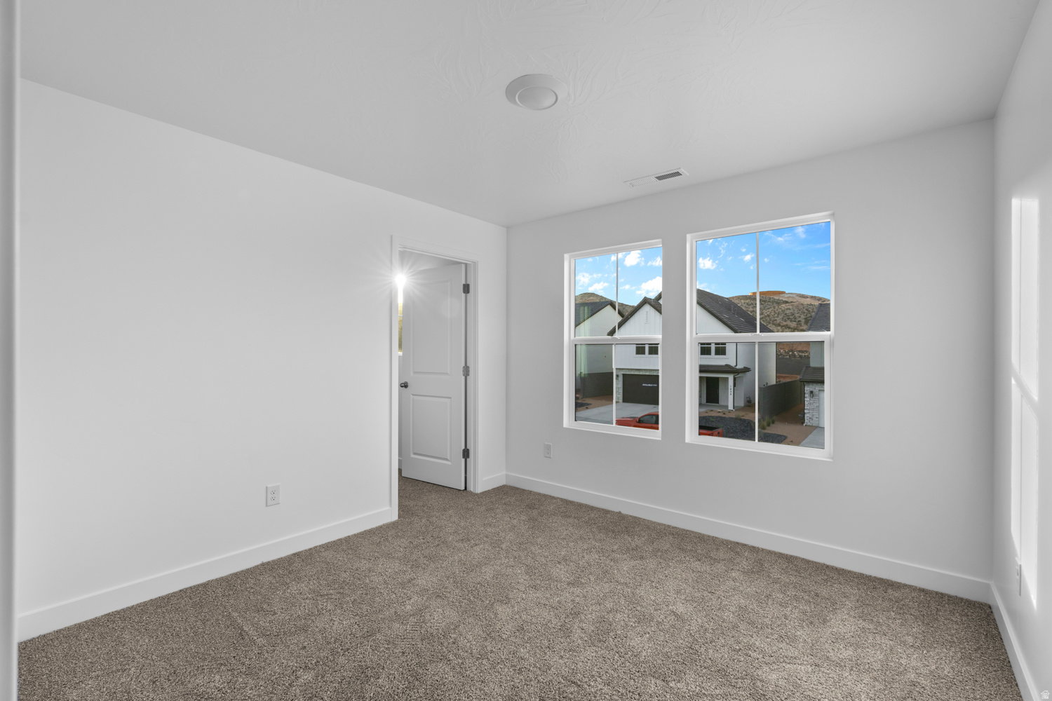 Bedroom with neutral carpet flooring, white painted walls, and white trim