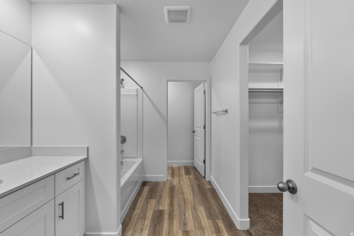 Bathroom featuring a single vanity with light-colored countertop, white cabinetry with dark hardware, and a tub/shower combination