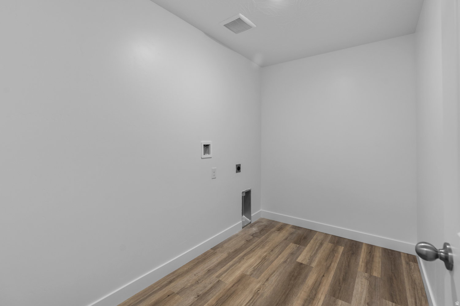 Dedicated utility space featuring wood-finish flooring and white baseboards