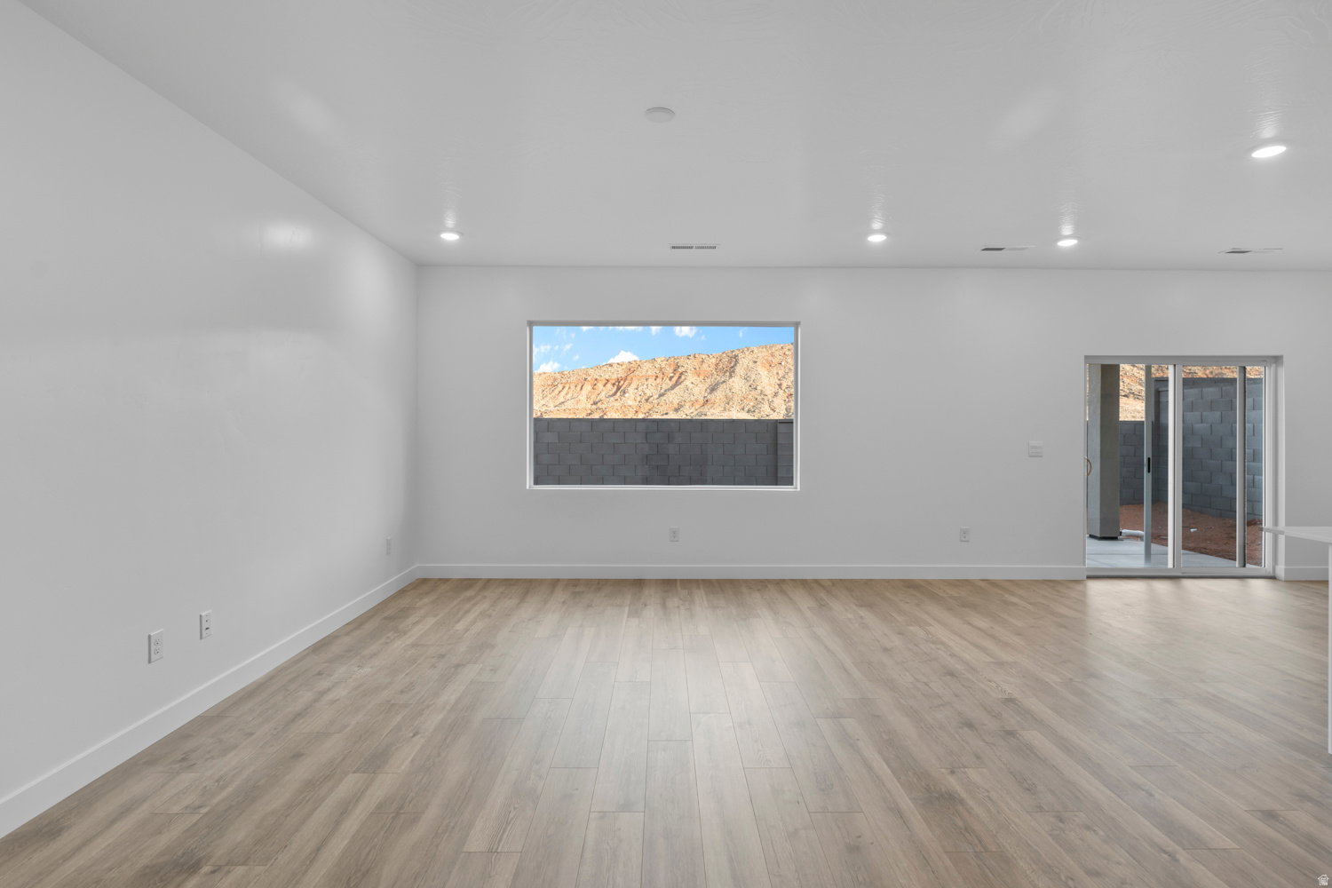 Spacious room featuring light wood-finish flooring, recessed lighting, and a neutral wall palette