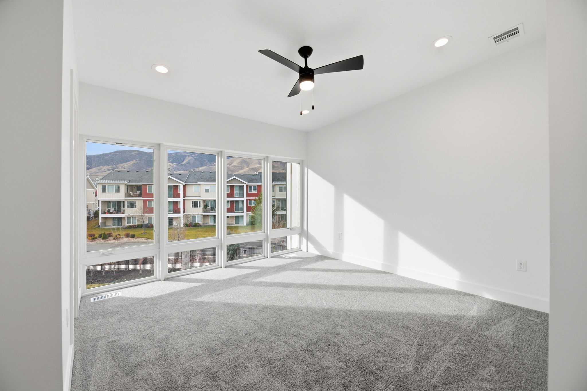Expansive room with wall-to-wall carpeting and a wide window array