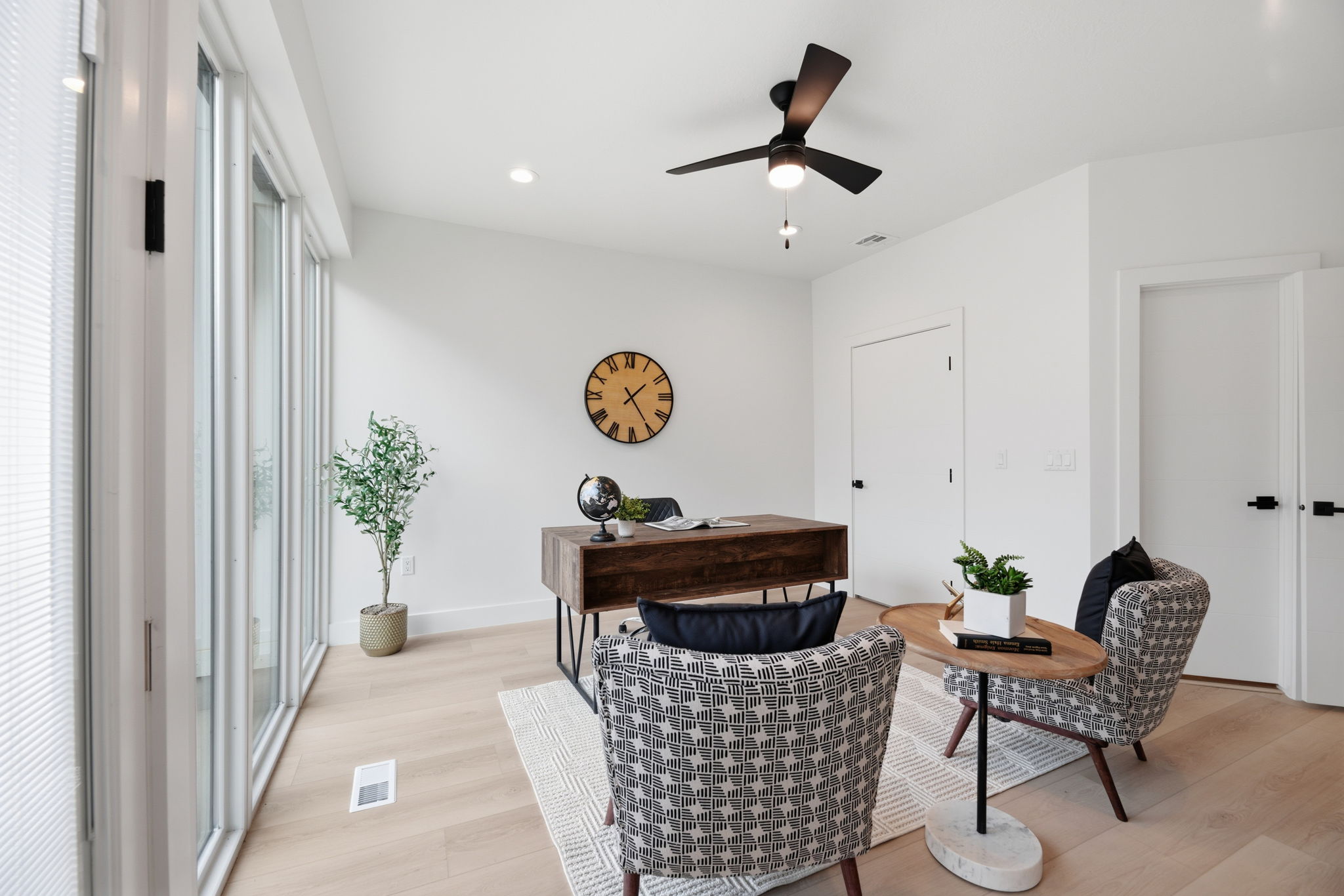 Bright room featuring expansive floor-to-ceiling windows, light wood-finish flooring, a modern ceiling fan, and recessed lighting