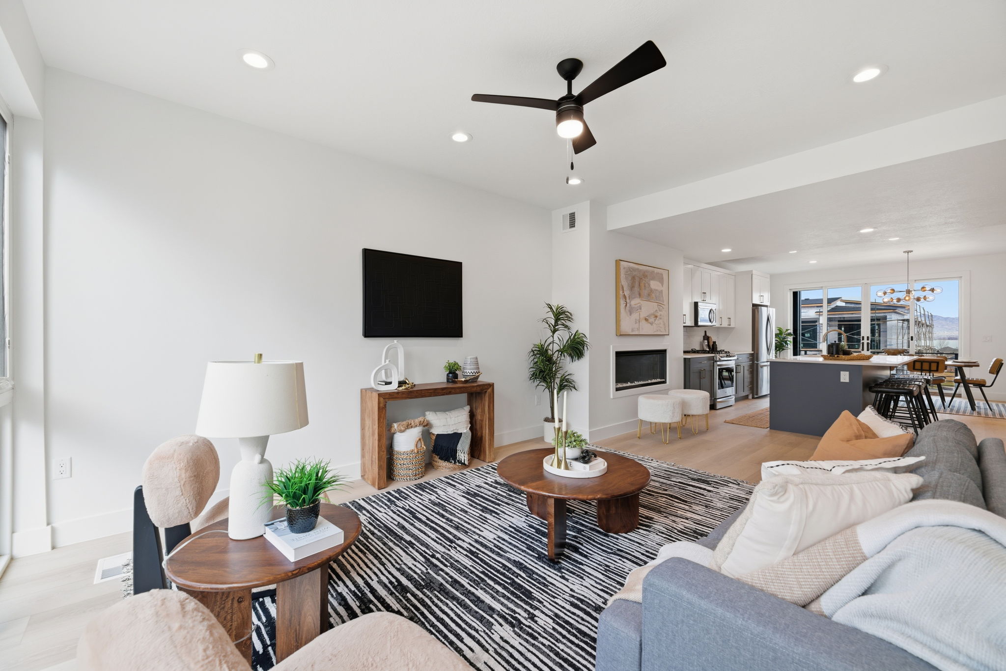 Open-concept living area featuring light wood-finish flooring, recessed lighting, and a contemporary ceiling fan