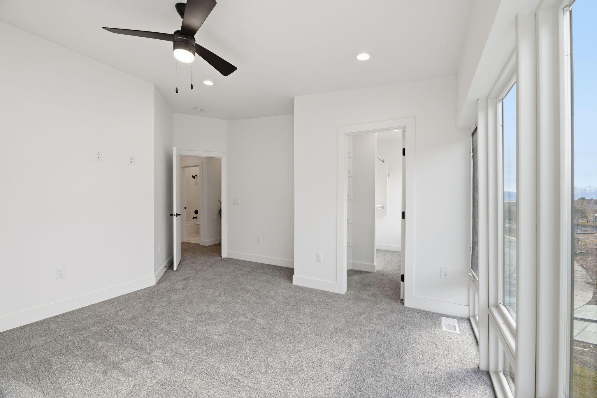 Room featuring light gray carpeting, white walls, and a modern black ceiling fan