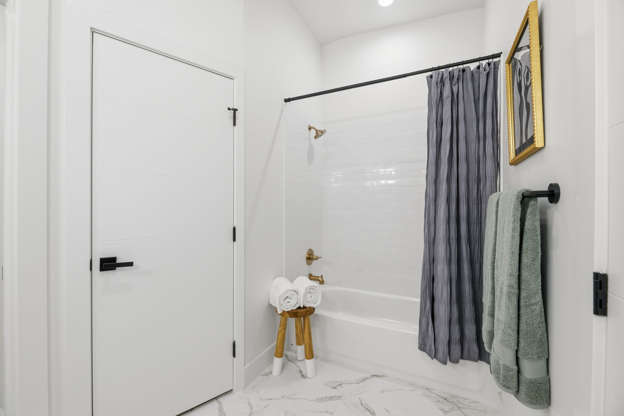 Bathroom featuring a white subway tile tub surround, bronze shower fixtures, a black-finish towel bar, and a white interior door with black hardware