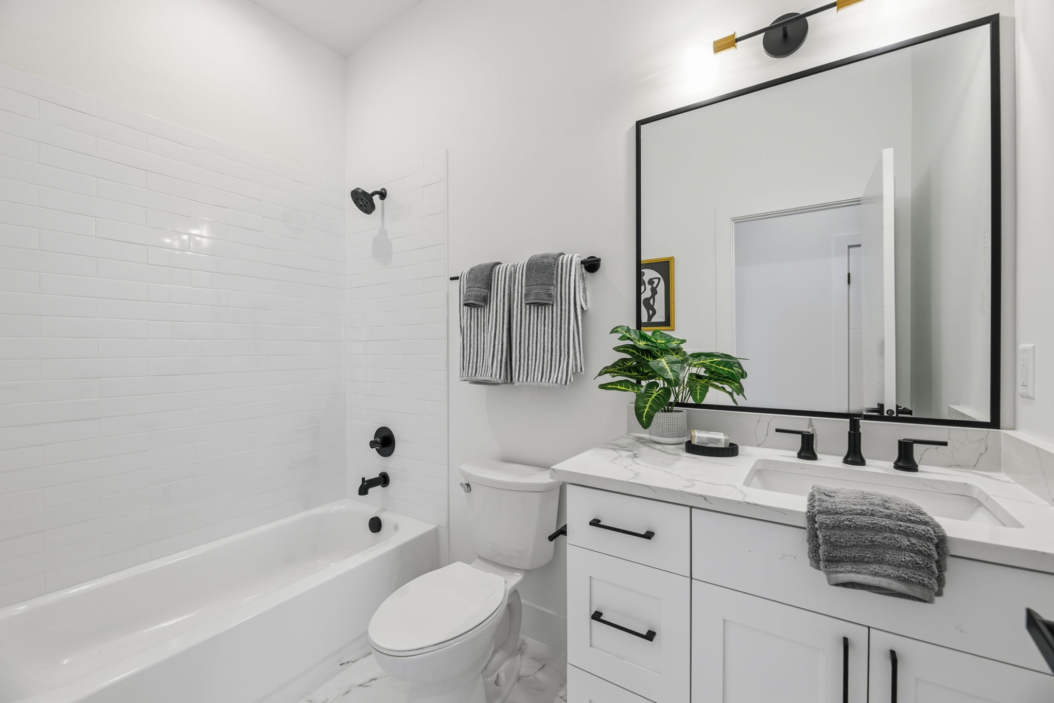Bathroom featuring a white subway tile shower surround, a white bathtub, and a modern vanity with a rectangular sink