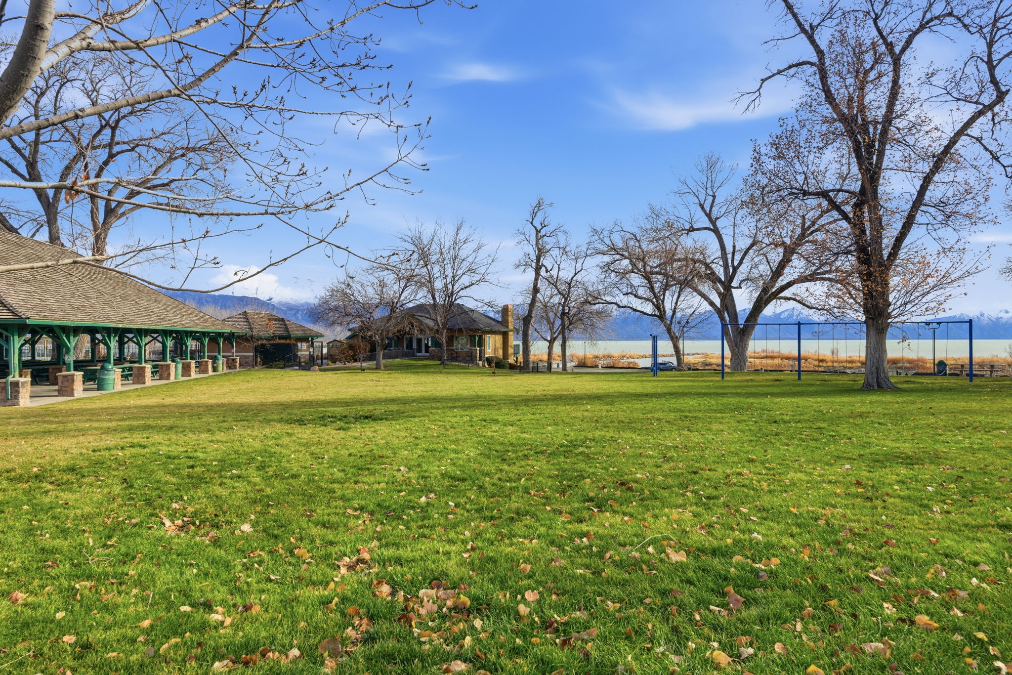 Expansive green lawn with mature trees and a distant mountain range backdrop