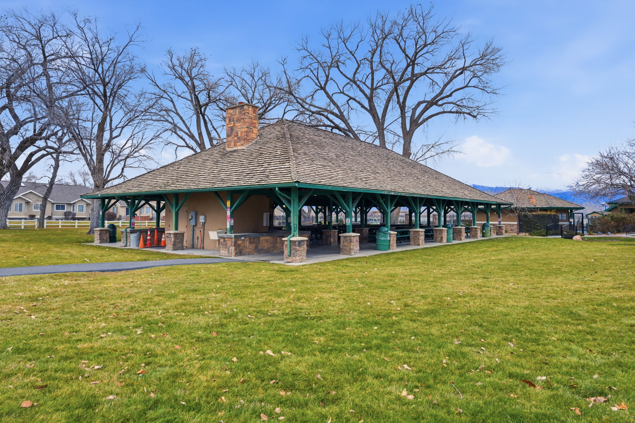 Expansive outdoor pavilion featuring a hipped roof, a brick chimney, and stone-clad pillars