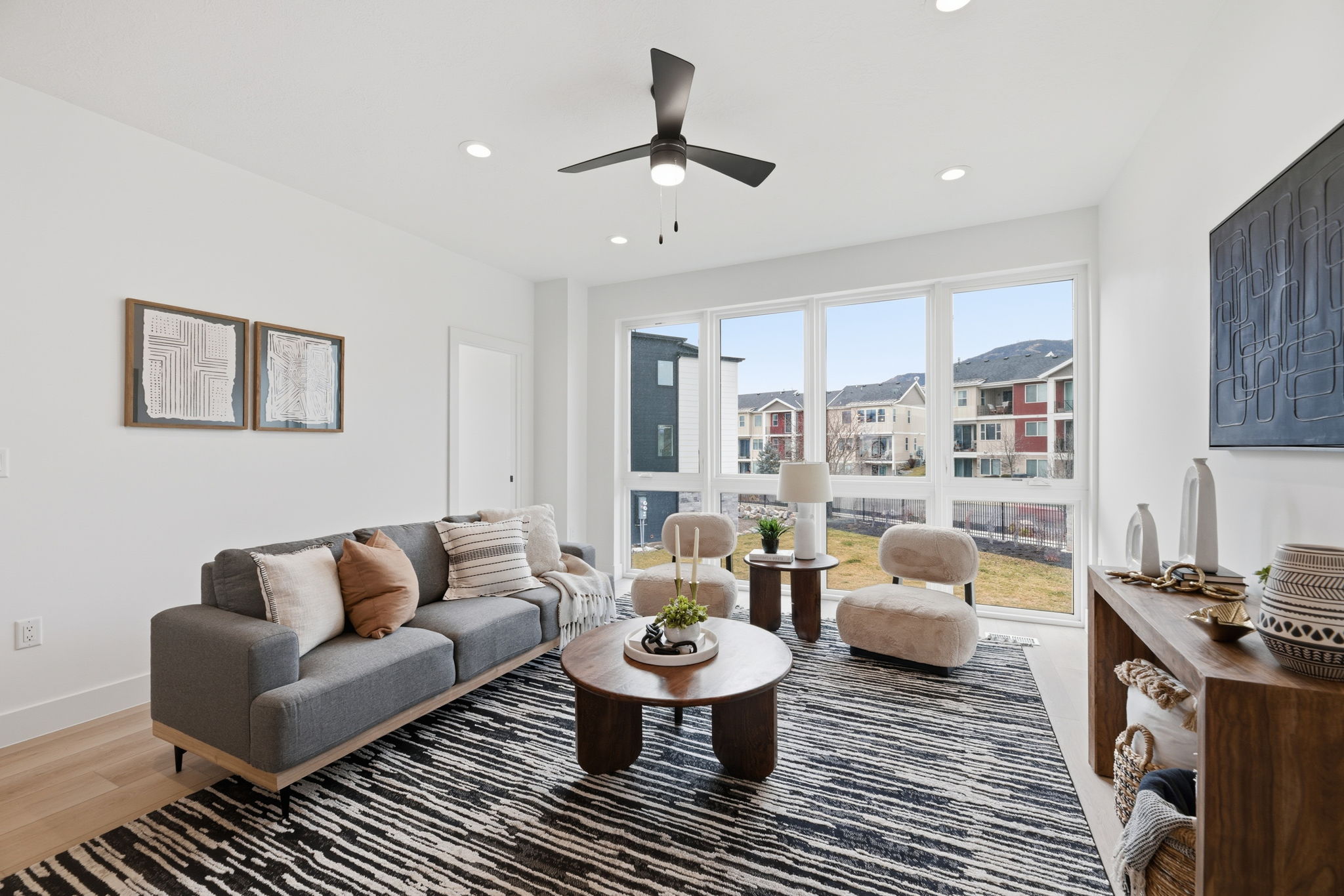 Open-concept living area featuring light wood-finish flooring, recessed lighting, and a modern ceiling fan
