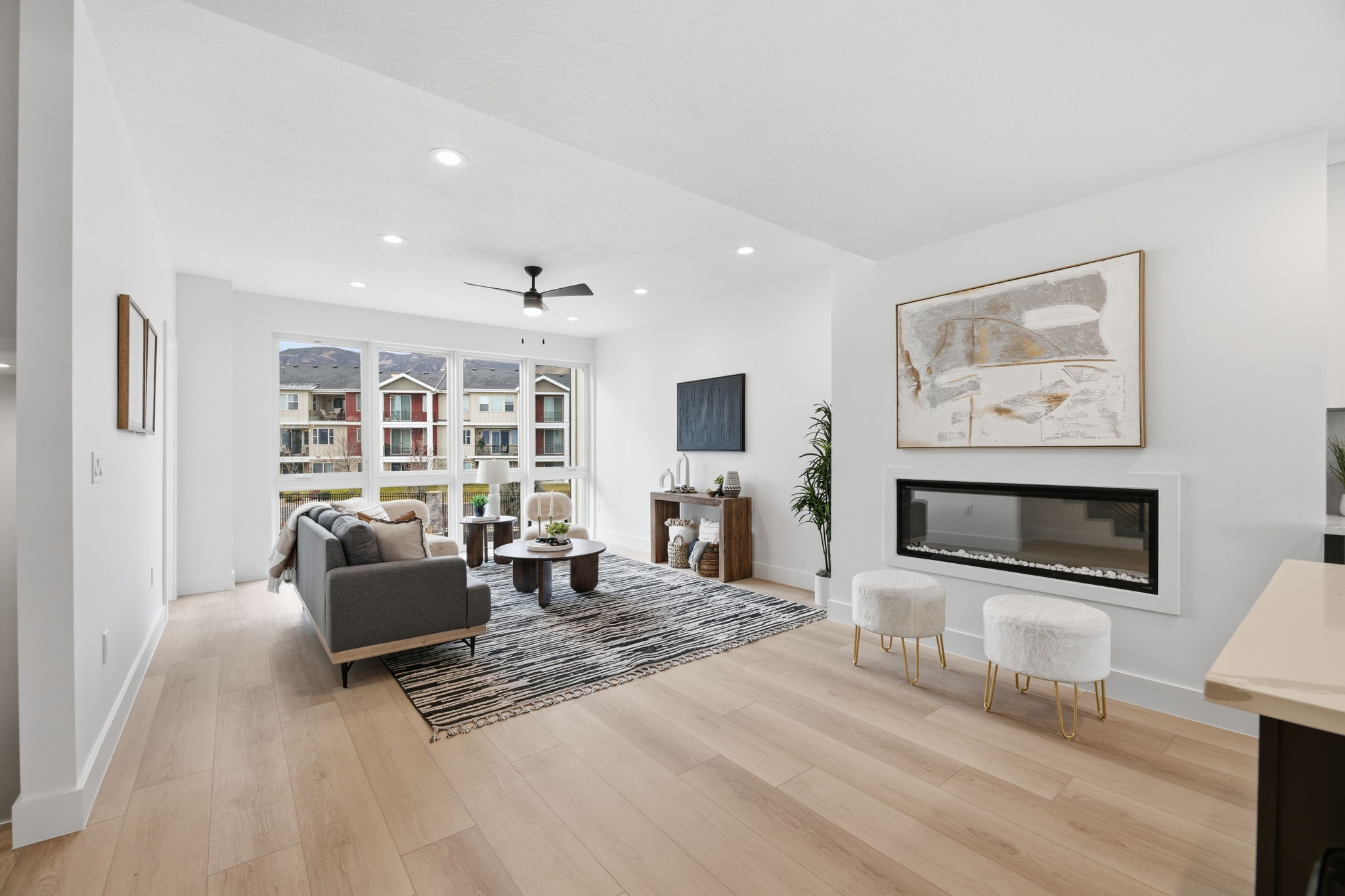 Spacious living area featuring large windows, wood-finish flooring, recessed lighting, and a modern linear fireplace
