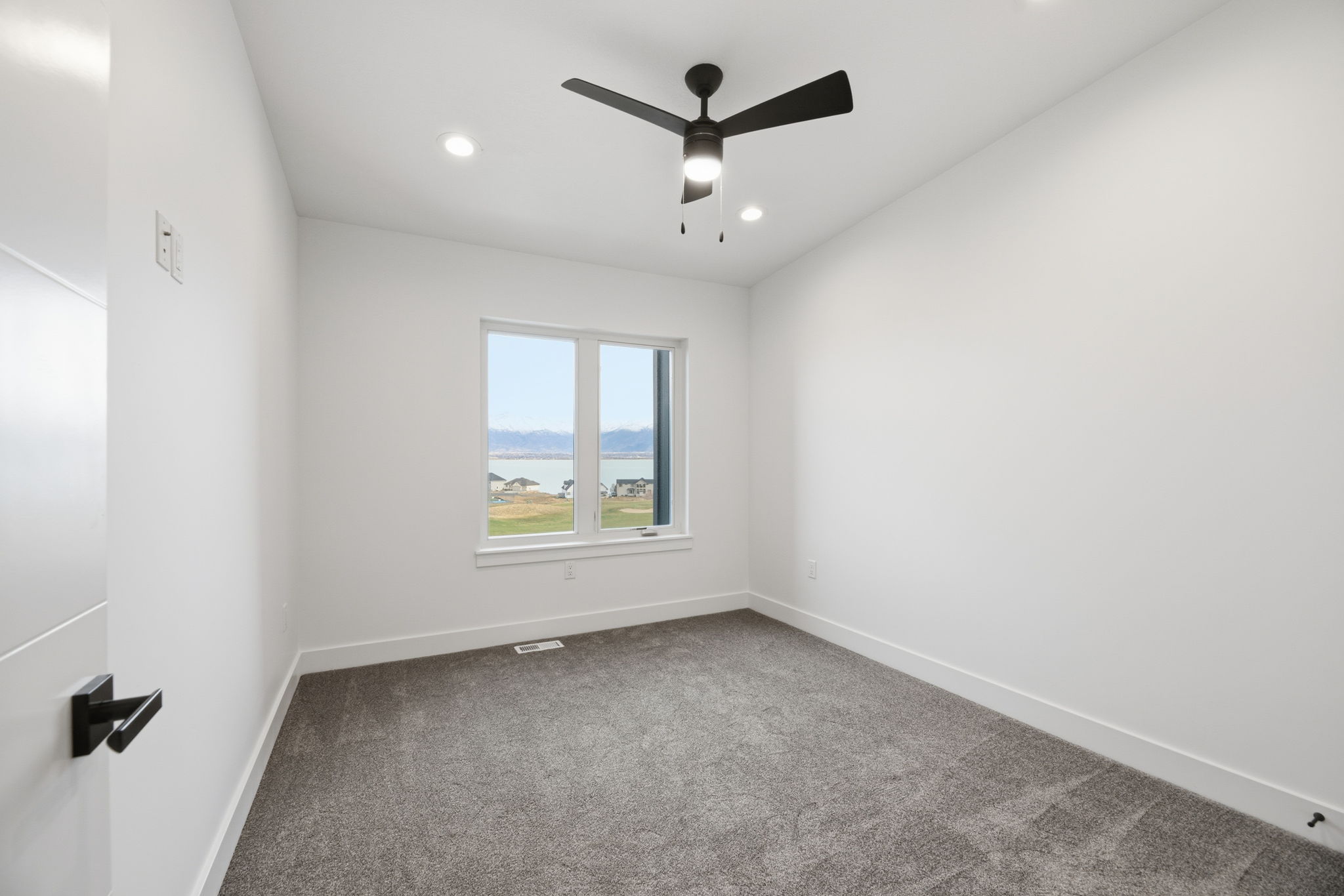 Room featuring a large window with a scenic water and mountain backdrop, recessed lighting, and a ceiling fan with integrated lighting