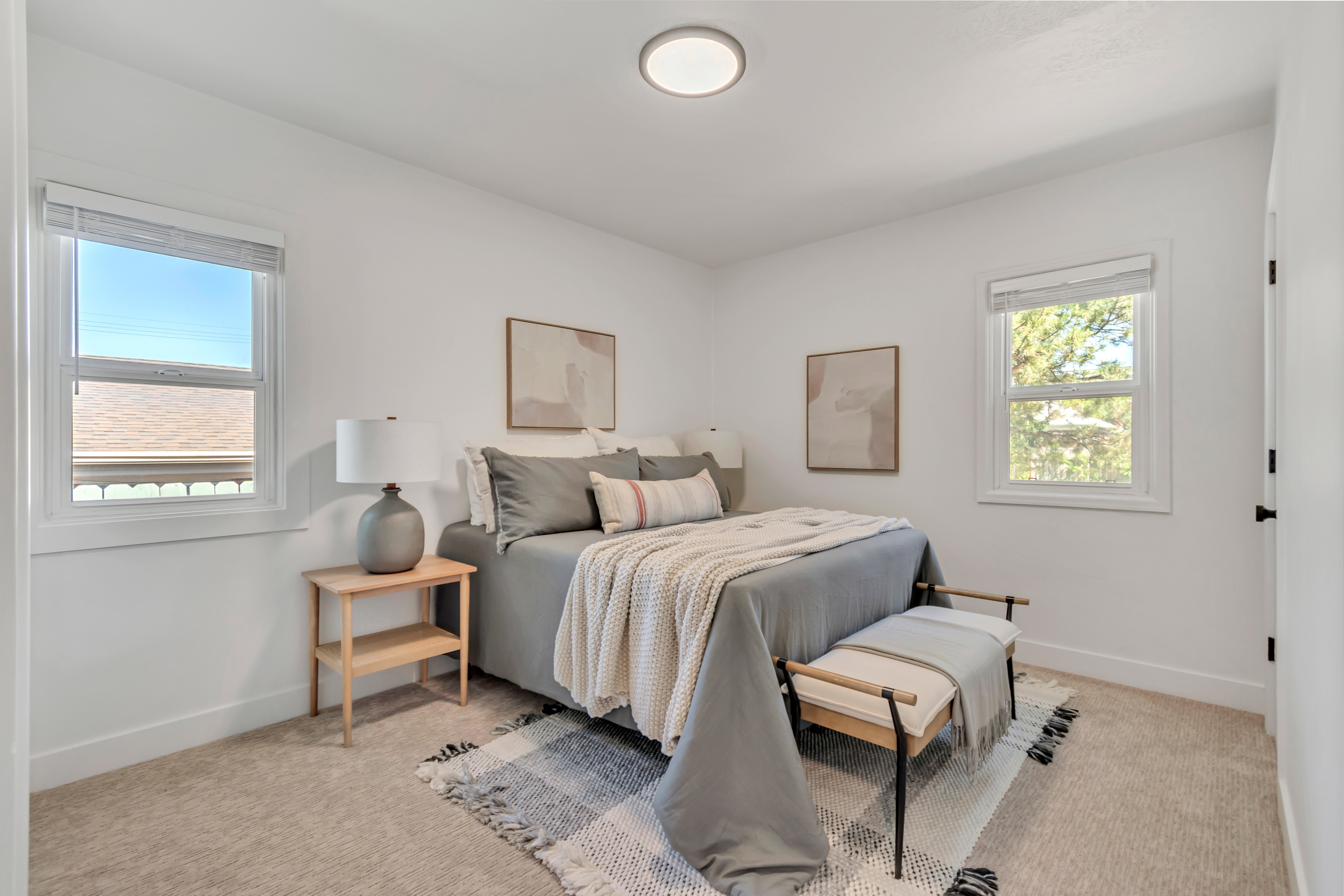 Bedroom featuring two windows, carpet flooring, a flush-mount ceiling light fixture, and white painted walls