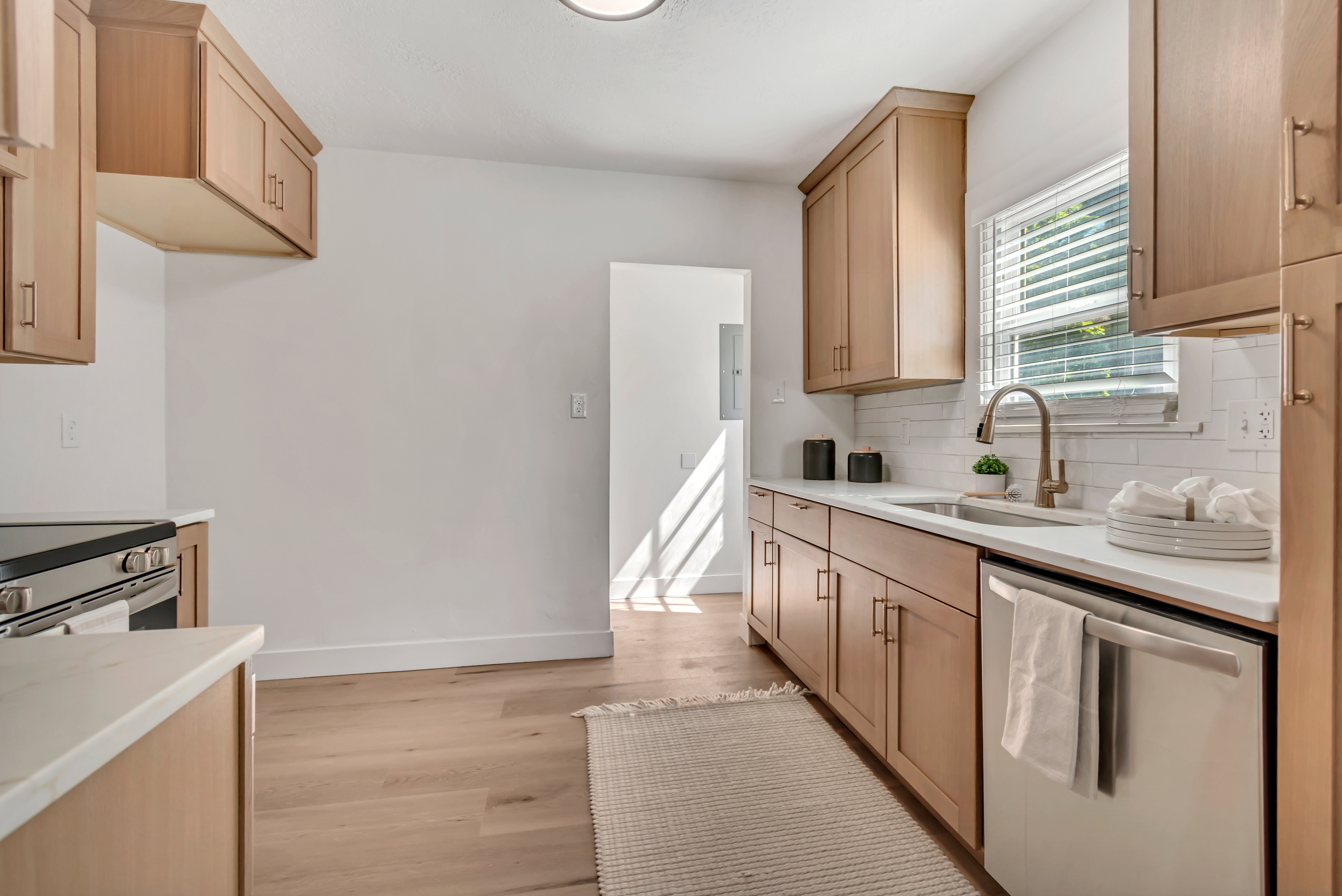Kitchen featuring light wood-finish cabinetry, white countertops, stainless steel appliances, and a tile backsplash