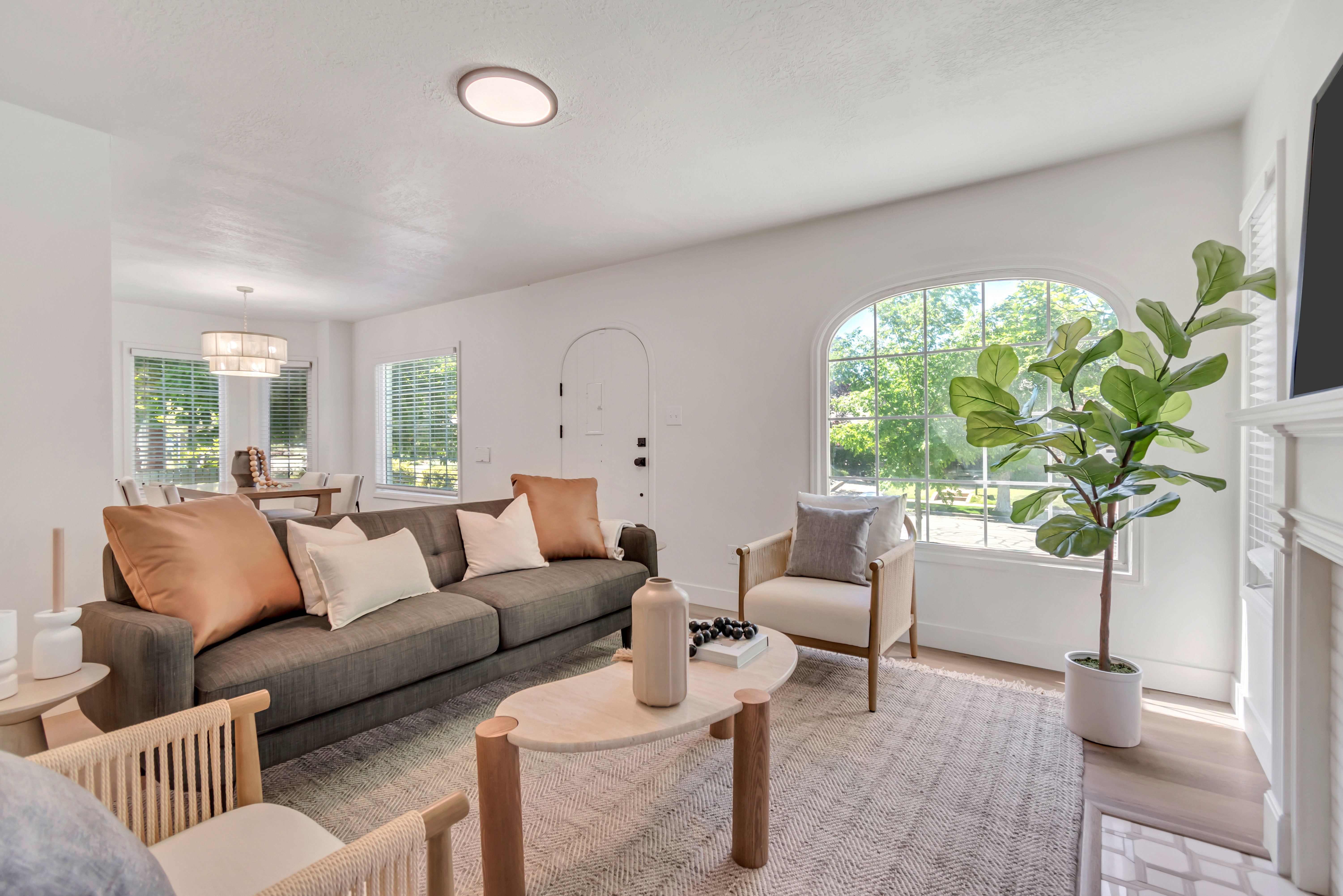 Living area featuring a prominent arched window, light wood-finish flooring, a white mantel, and an arched doorway