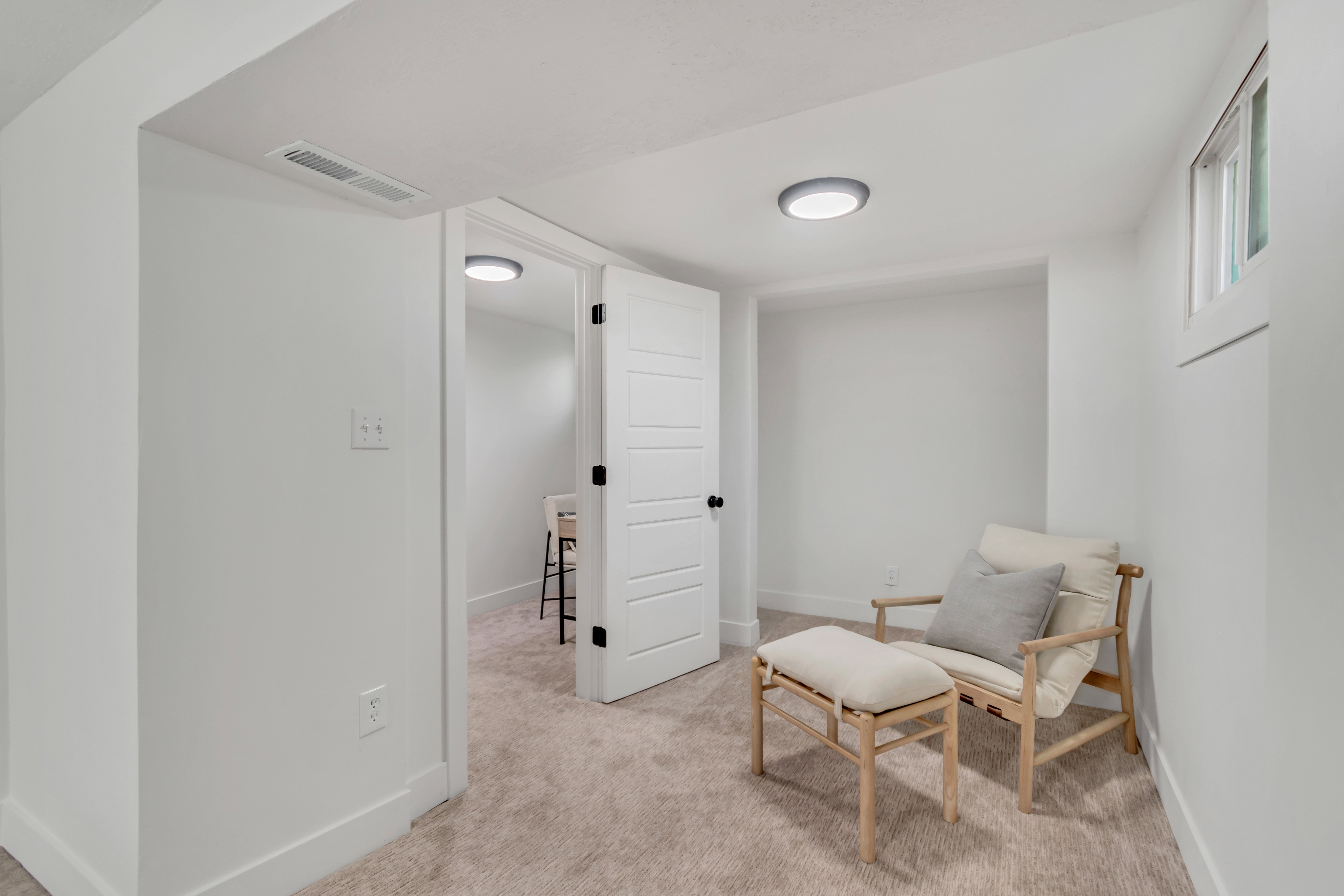 Carpeted room featuring white walls, a single window, and a modern paneled door with black hardware