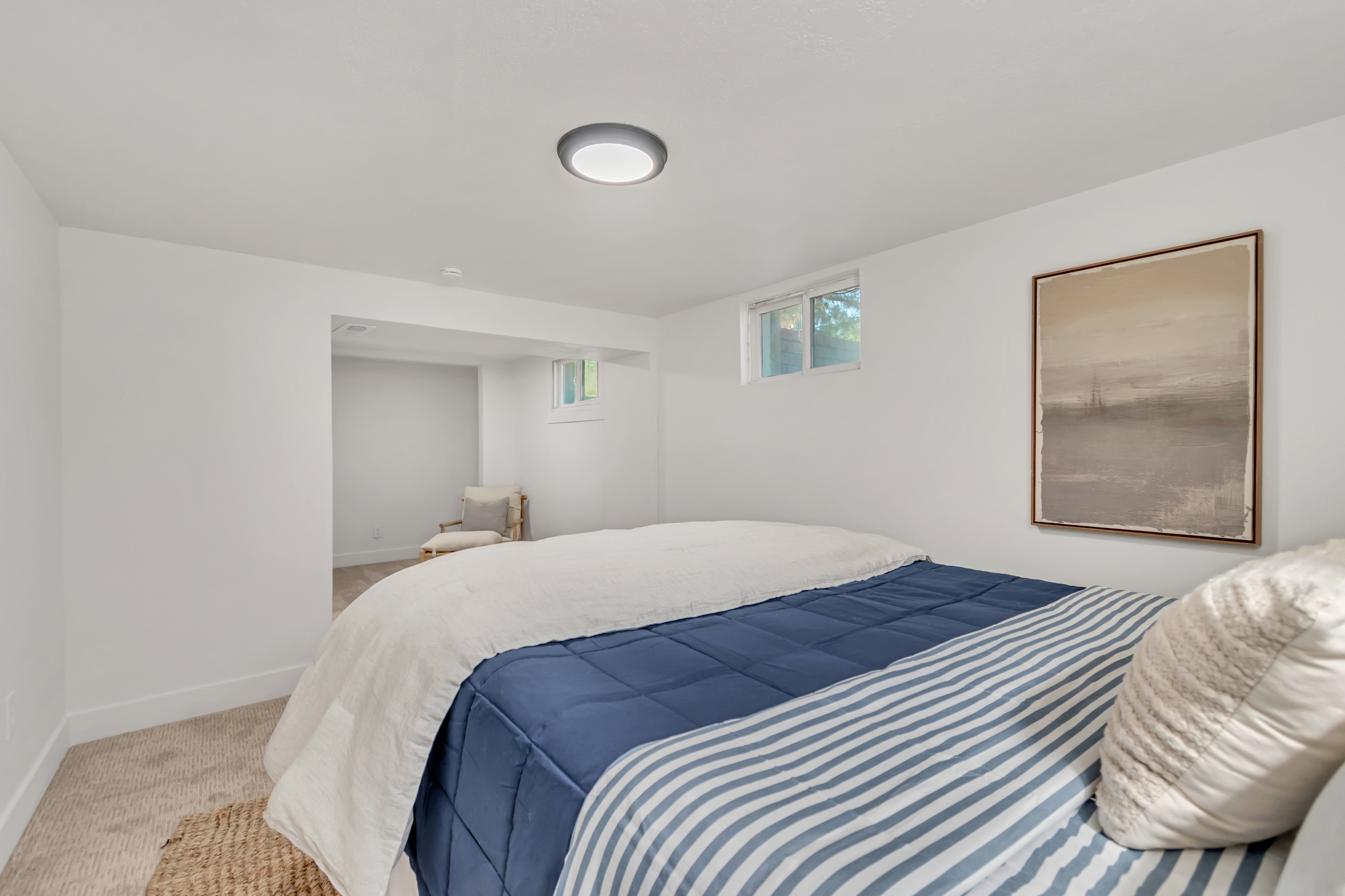 Carpeted bedroom featuring white walls, a single flush-mount ceiling light, and a horizontal window