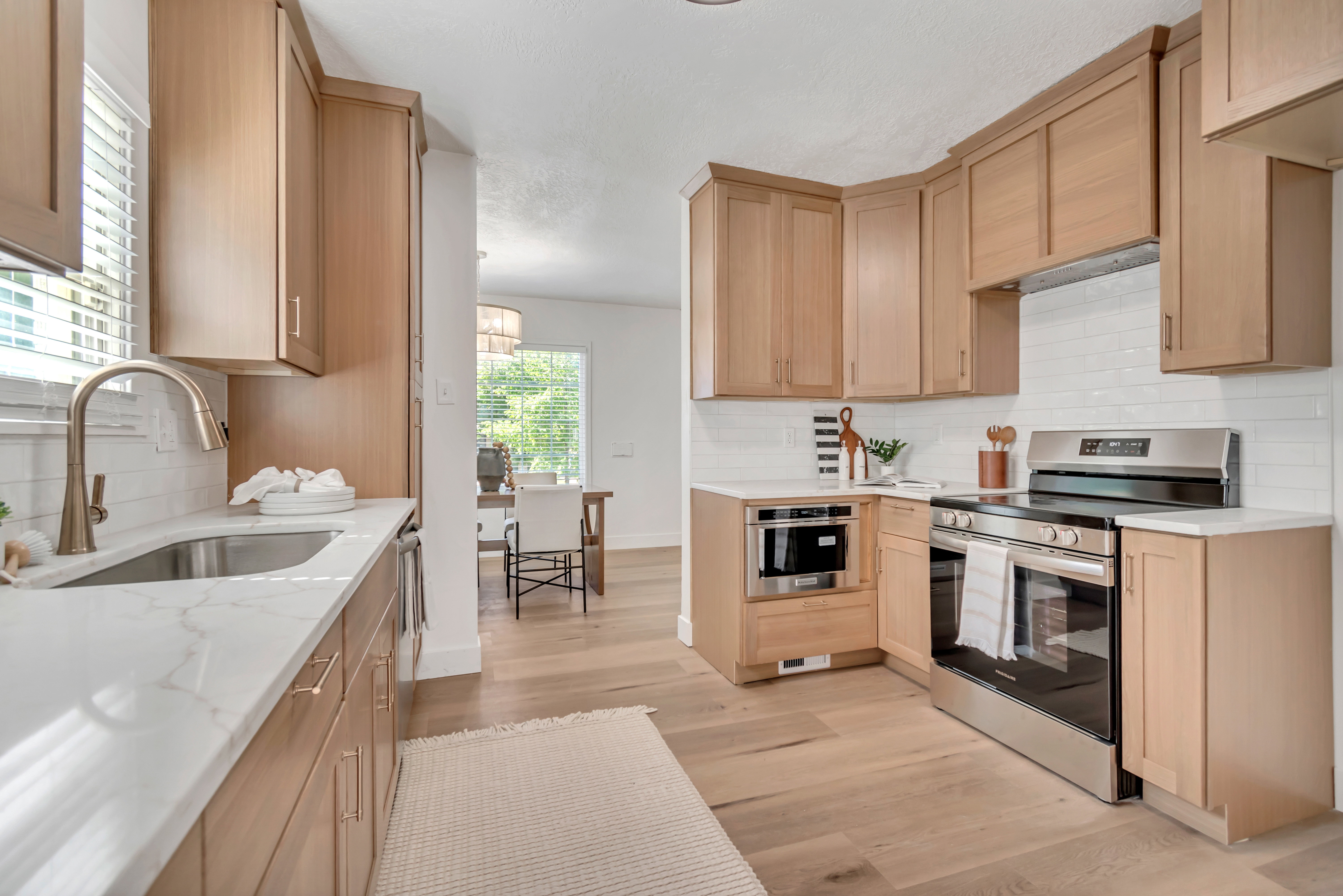 Modern kitchen featuring light wood-finish cabinetry, white countertops, and a white subway tile backsplash
