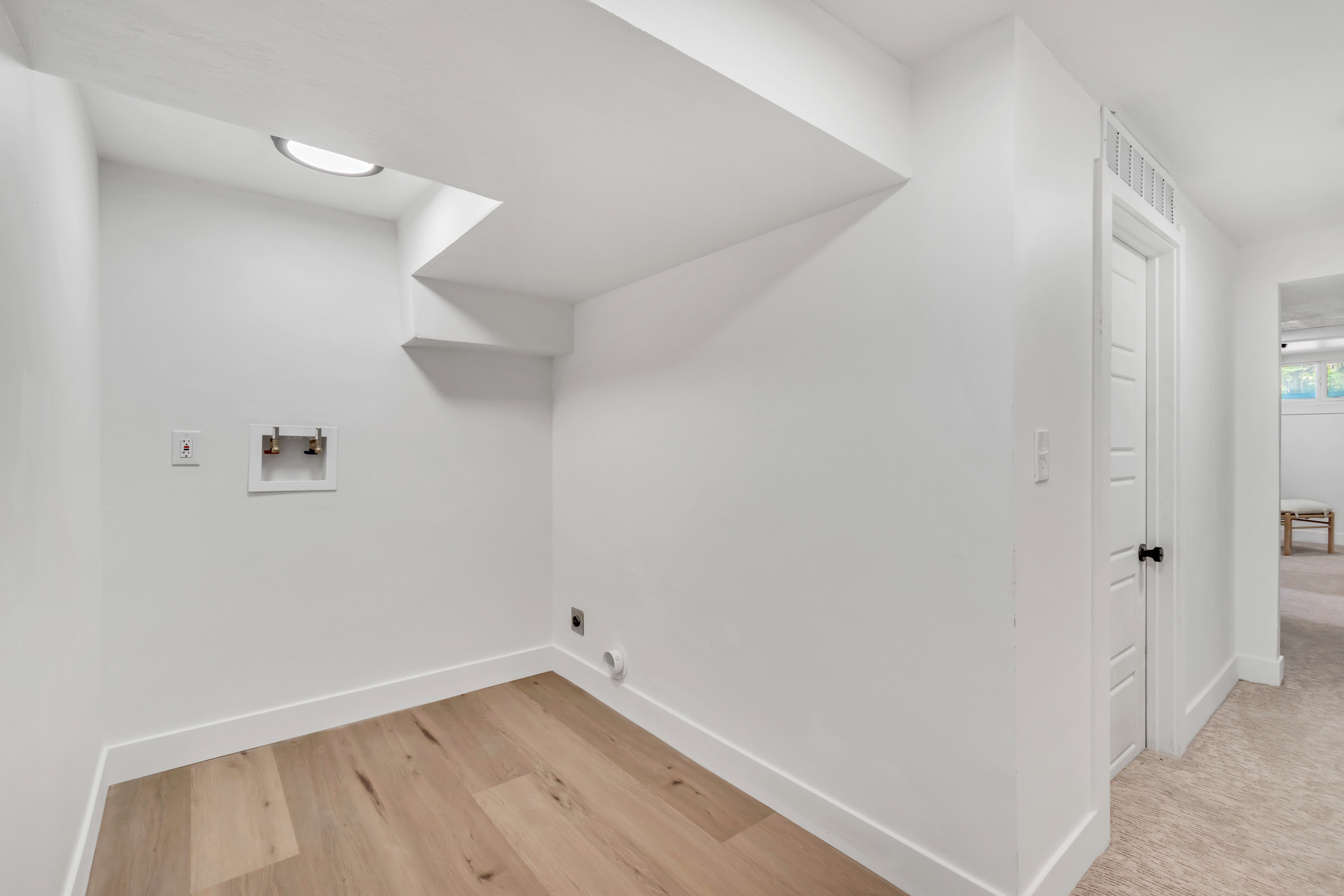 Dedicated laundry area featuring wood-finish flooring, white walls, and a ceiling-mounted light fixture