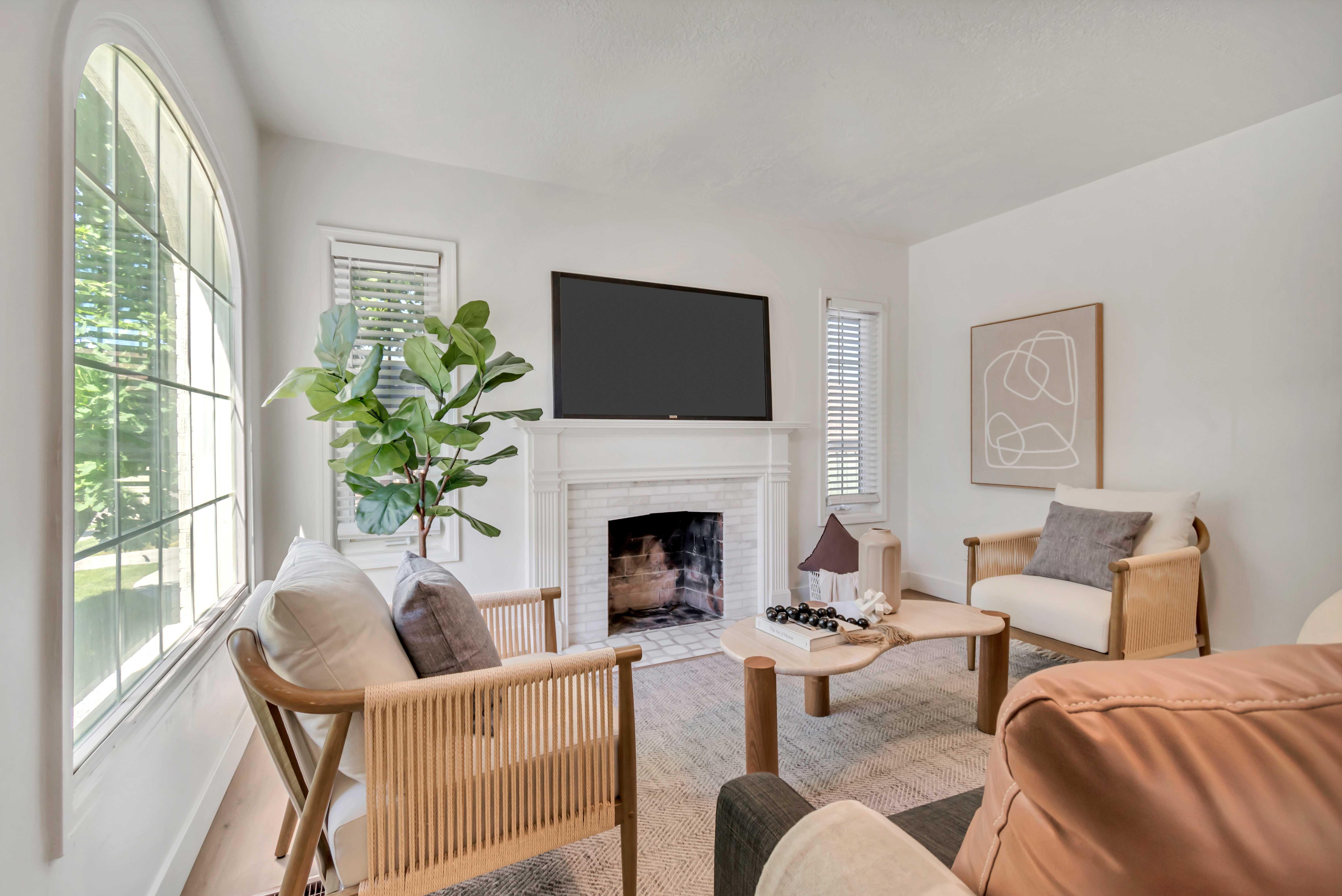 Living area featuring a fireplace with a white mantel, an arched window, and light wood-finish flooring