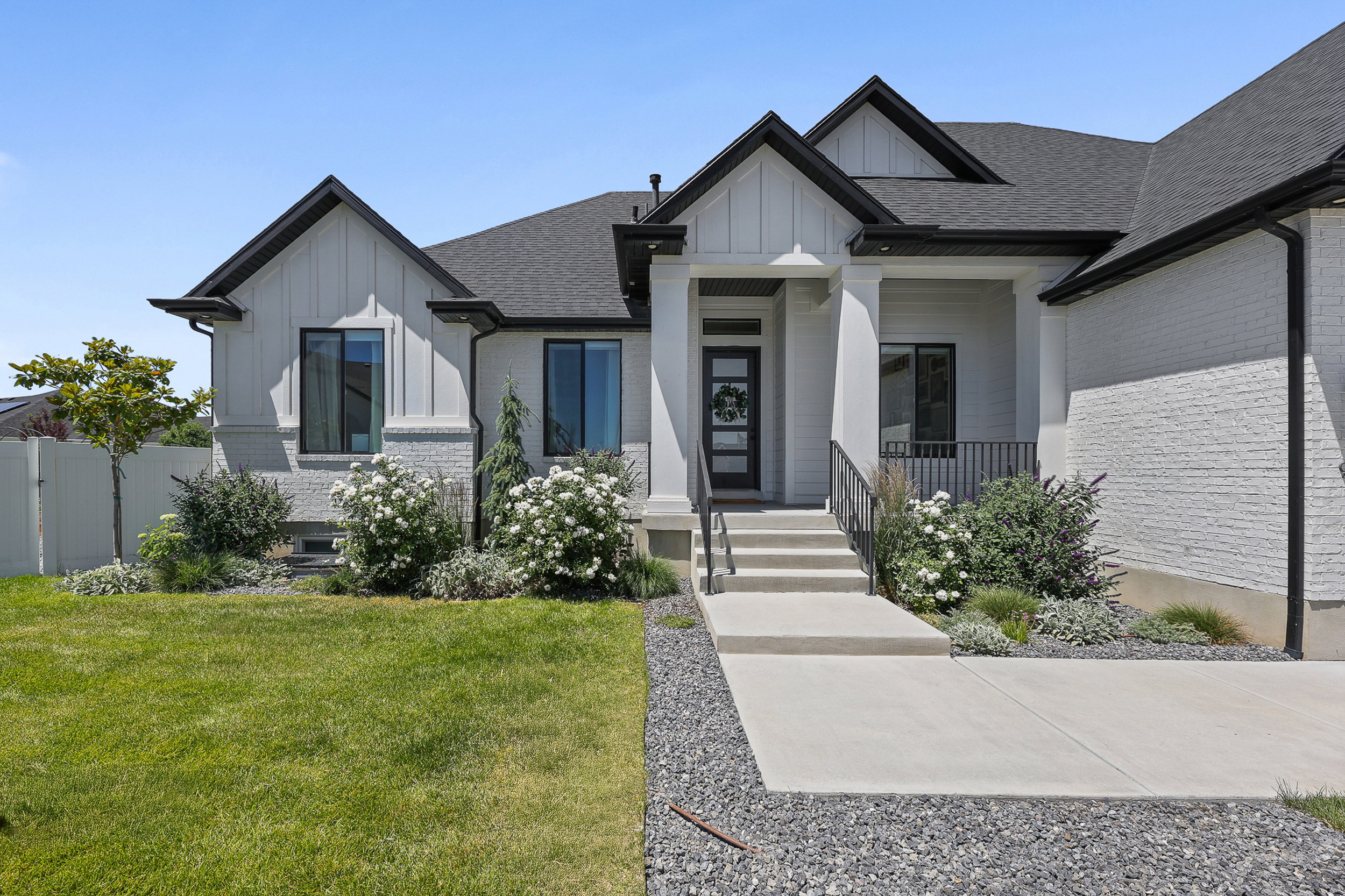 Contemporary single-story residence featuring white painted brick and vertical siding accents
