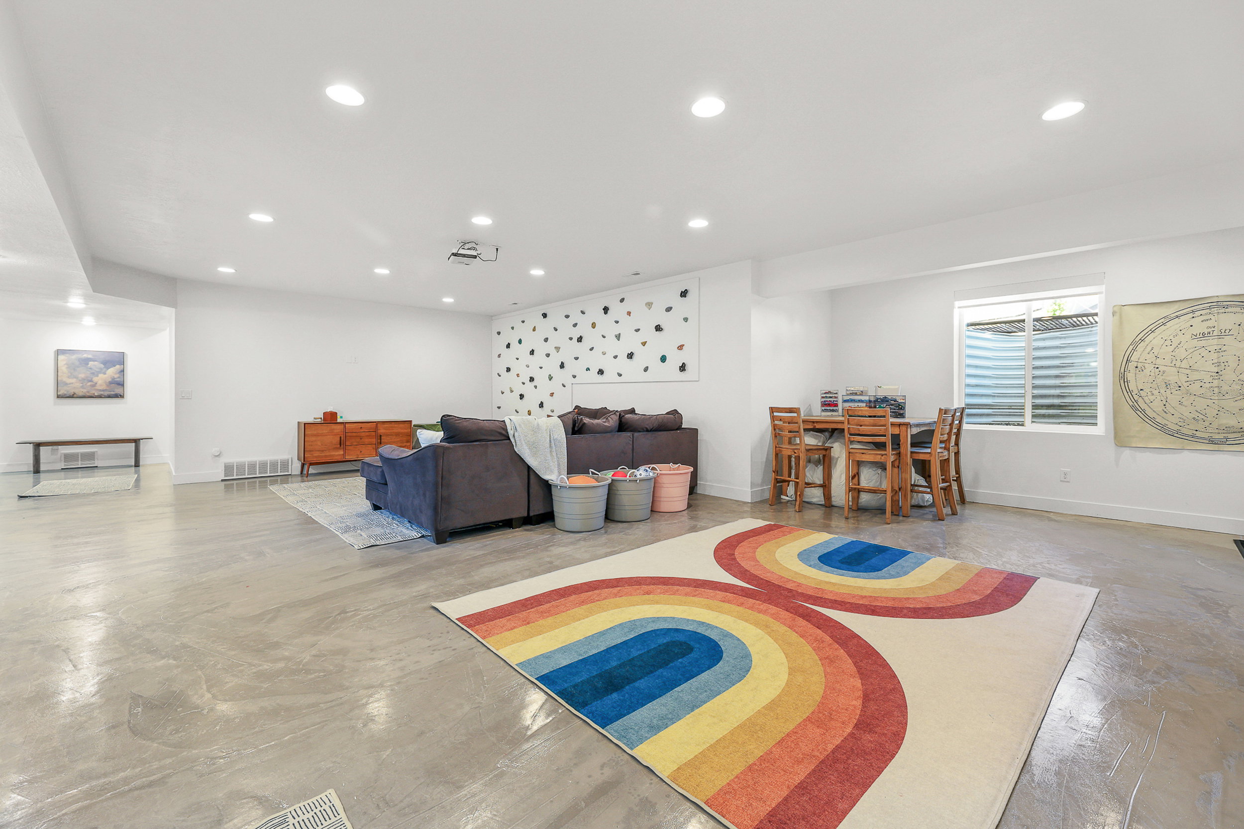 Spacious open-concept room featuring concrete flooring, recessed lighting, and a window with blinds
