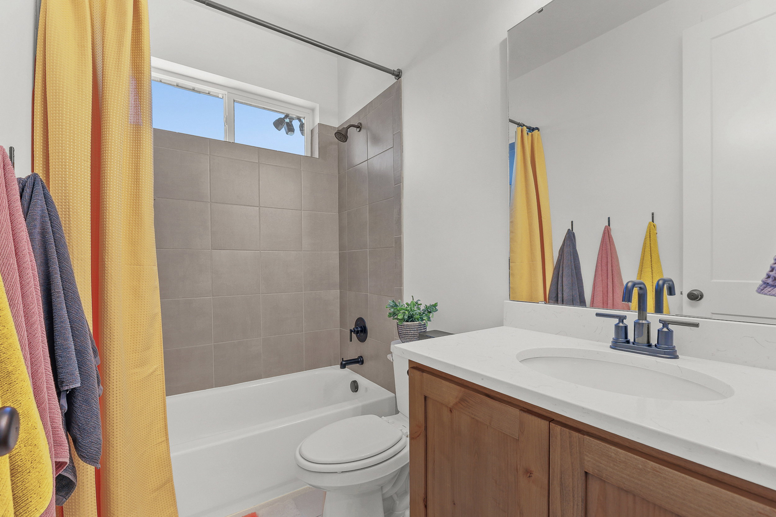 Bathroom featuring a wood-finish vanity with a white countertop, an undermount sink, and a dark-toned faucet