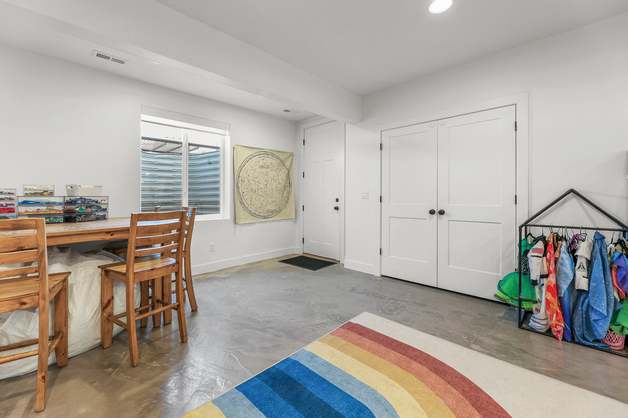 Bright room with concrete flooring, a window well, and multiple white paneled doors
