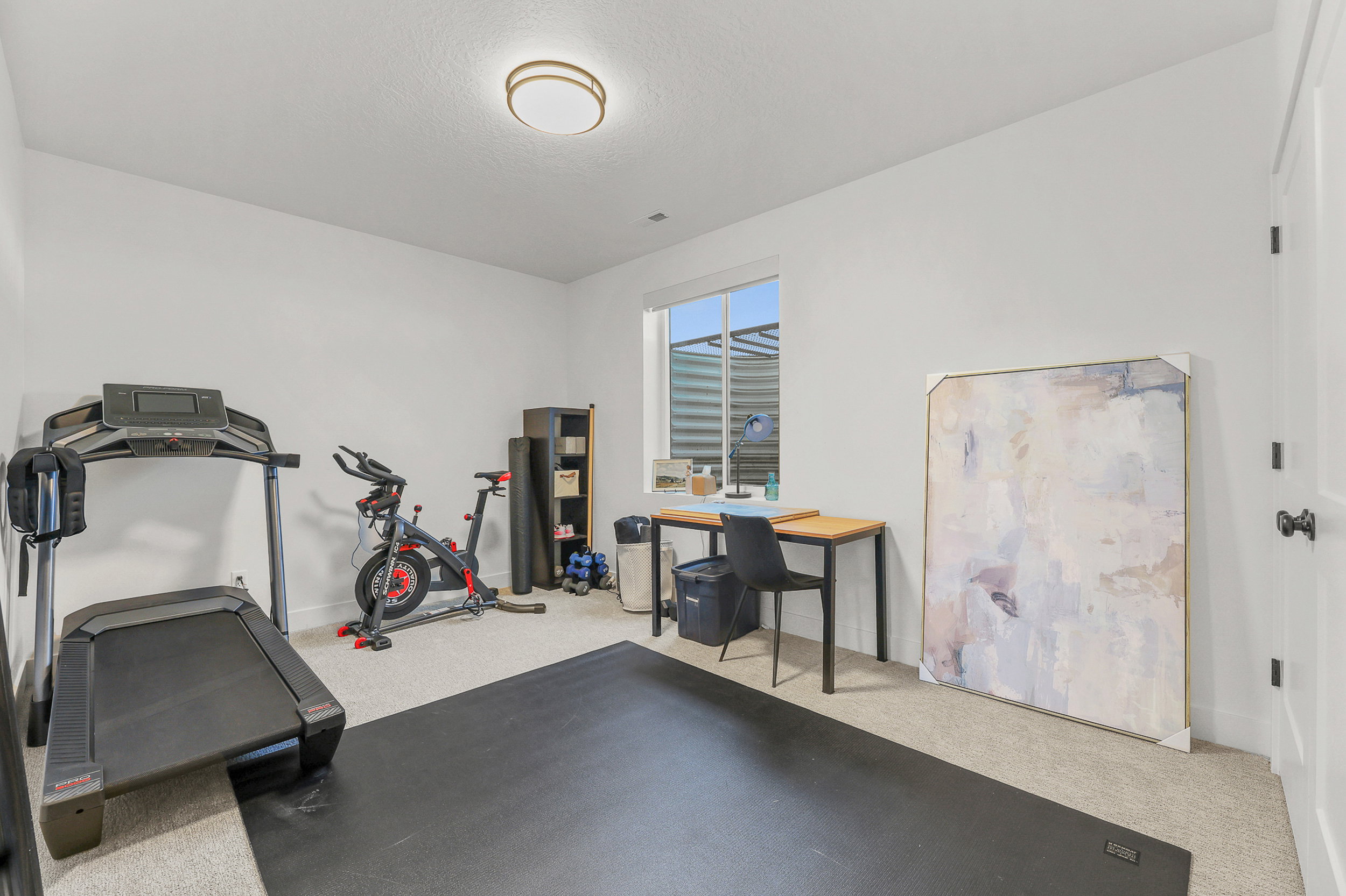 Versatile interior space featuring light-colored carpeting, a single window with a horizontal blind, and recessed lighting