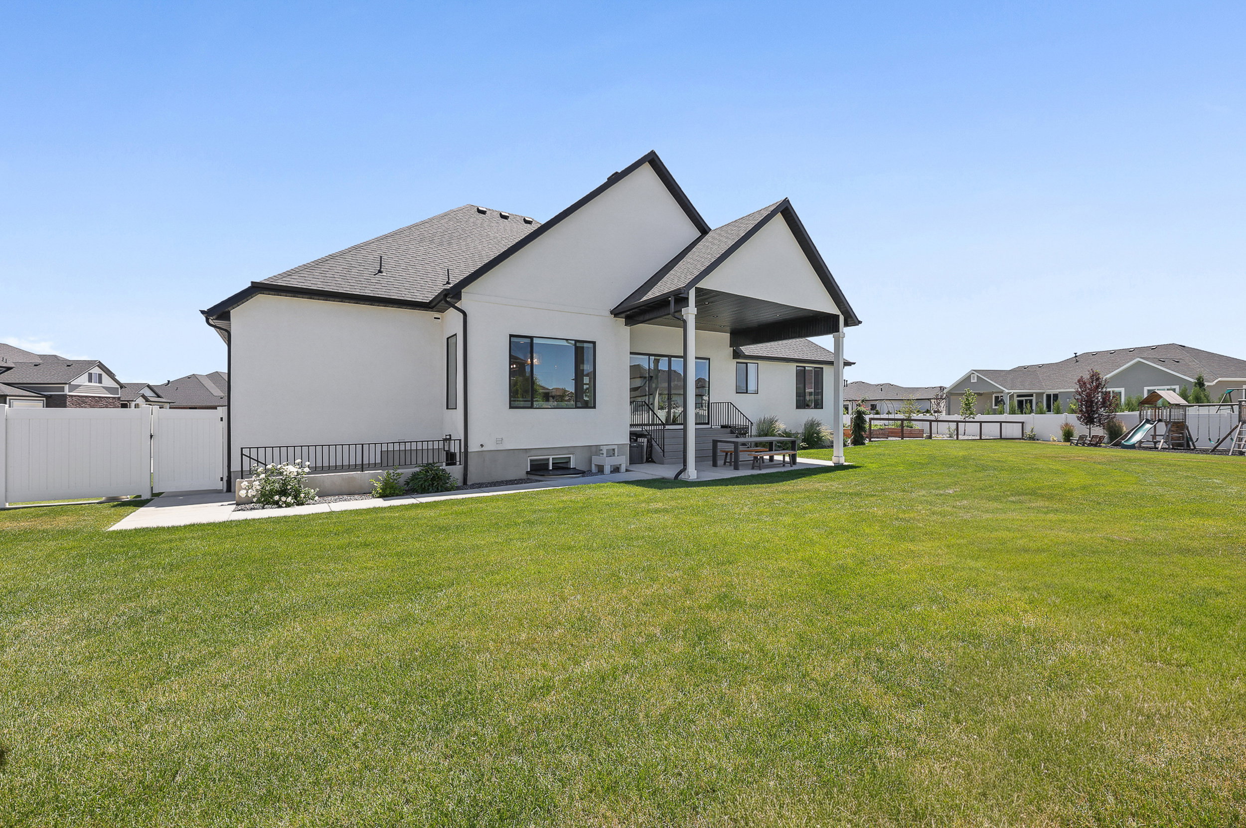 Expansive rear yard featuring a large green lawn and a covered patio