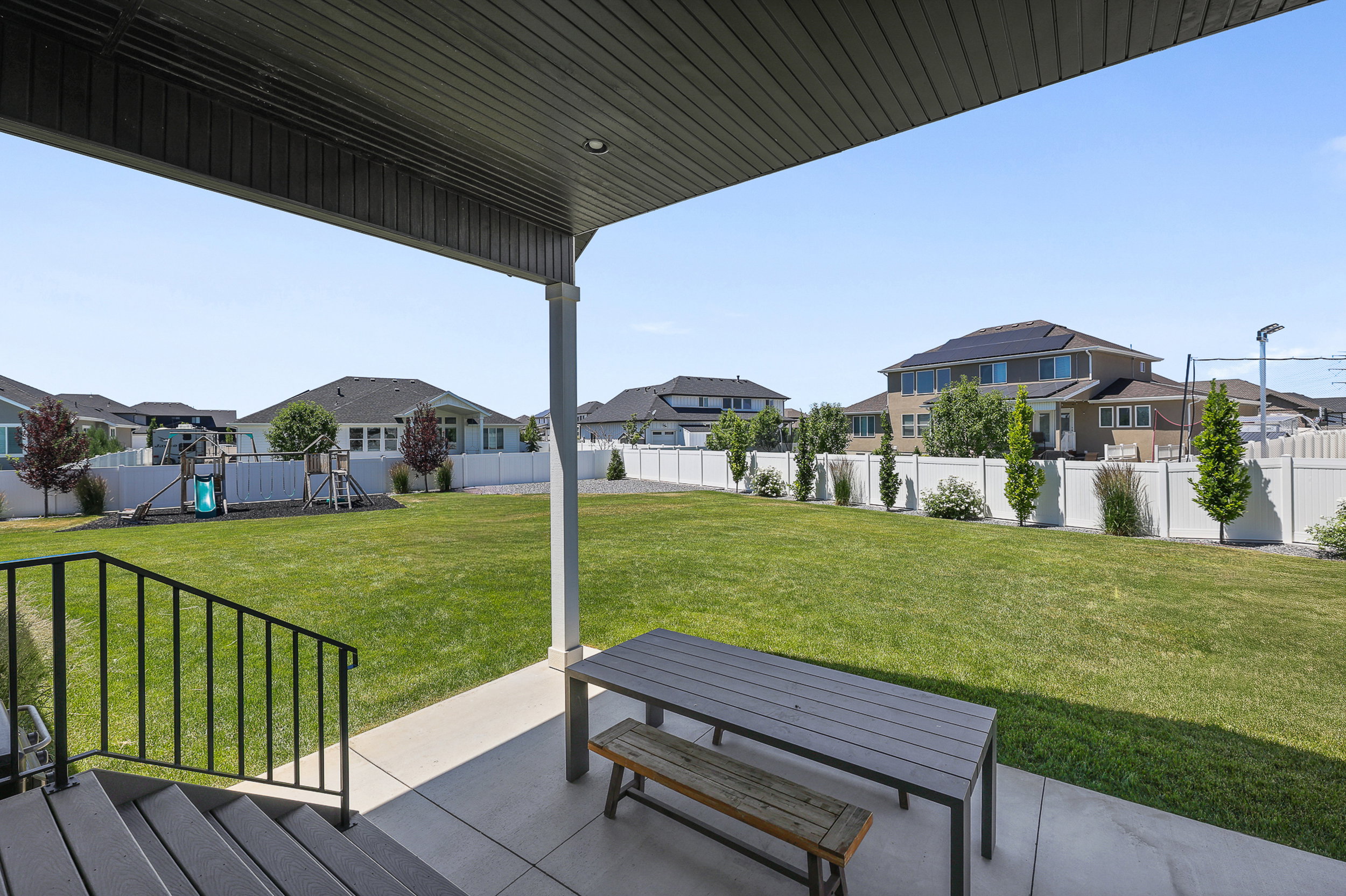 Covered patio with a concrete surface, black metal railings, and steps with composite decking