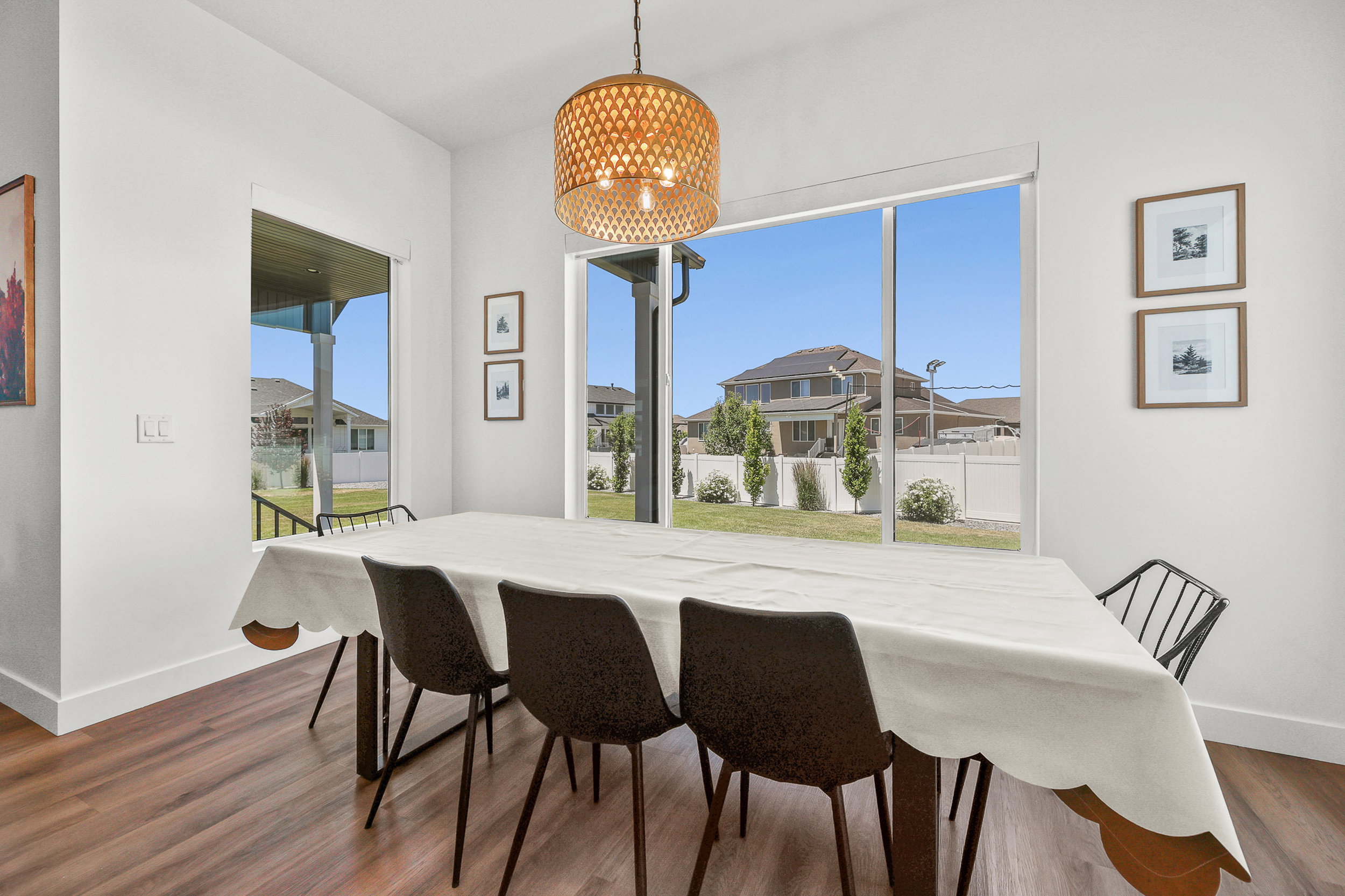 Dining area featuring large windows, wood-finish flooring, and a decorative pendant light fixture