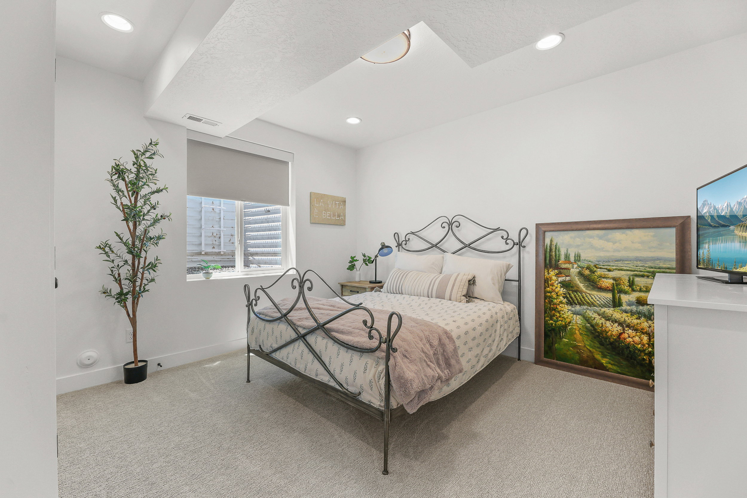 Recessed ceiling lighting illuminates the room, featuring plush carpet flooring and clean white walls