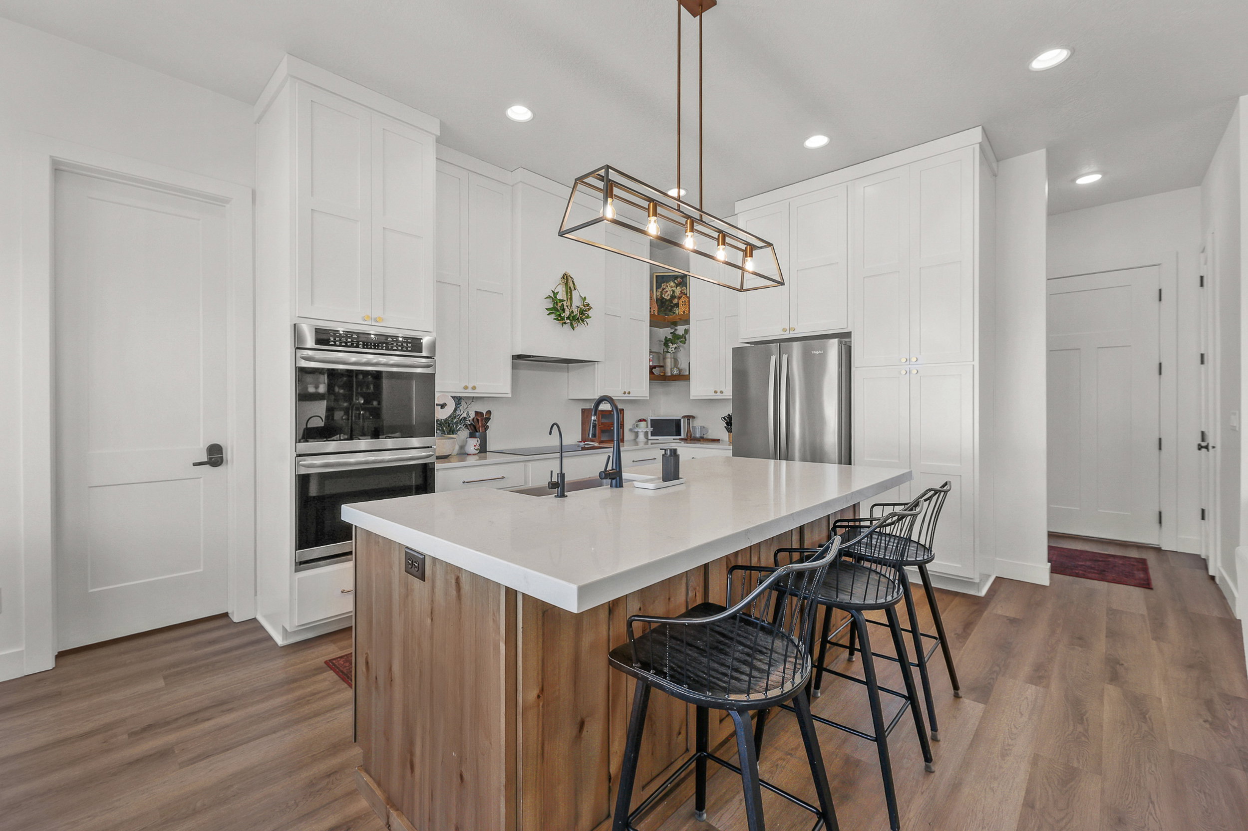 Modern kitchen featuring a large central island with a light-toned countertop and wood-finish paneling