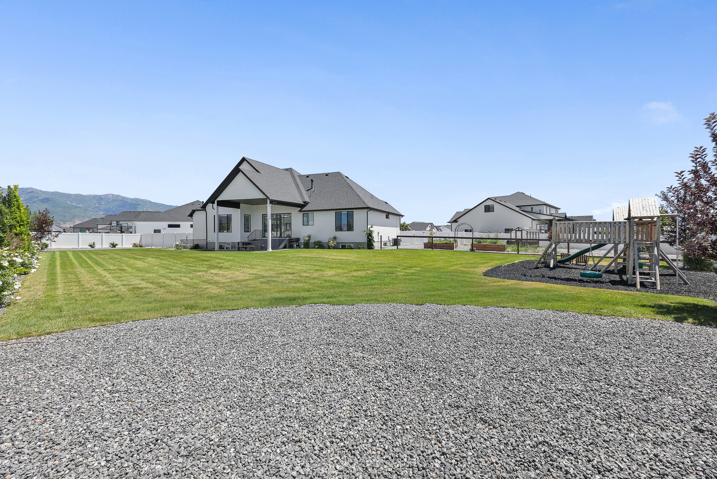 Expansive backyard featuring a large lawn, covered patio, and gravel area