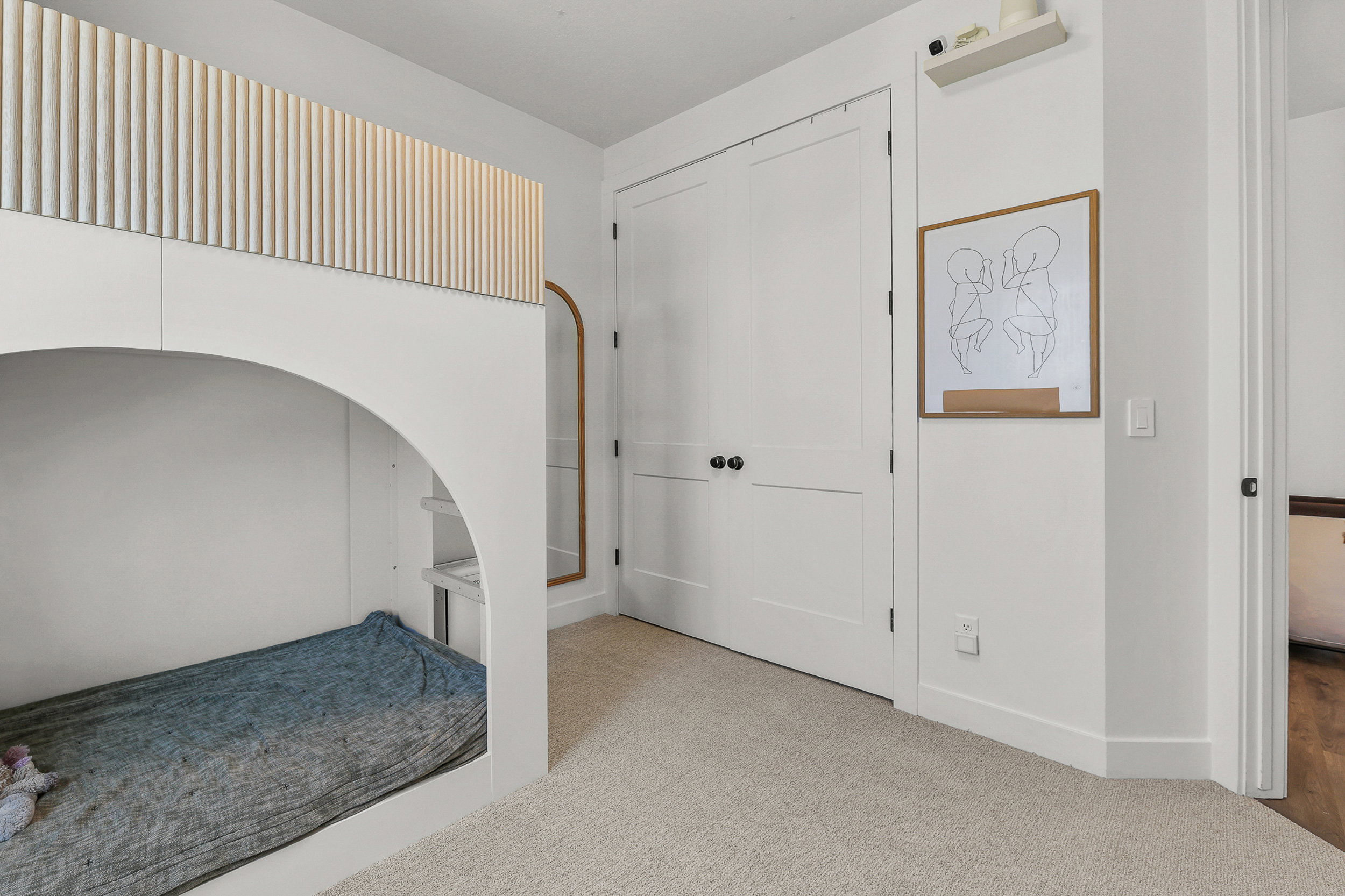 Built-in bunk bed with an arched opening and a fluted wood-finish top panel