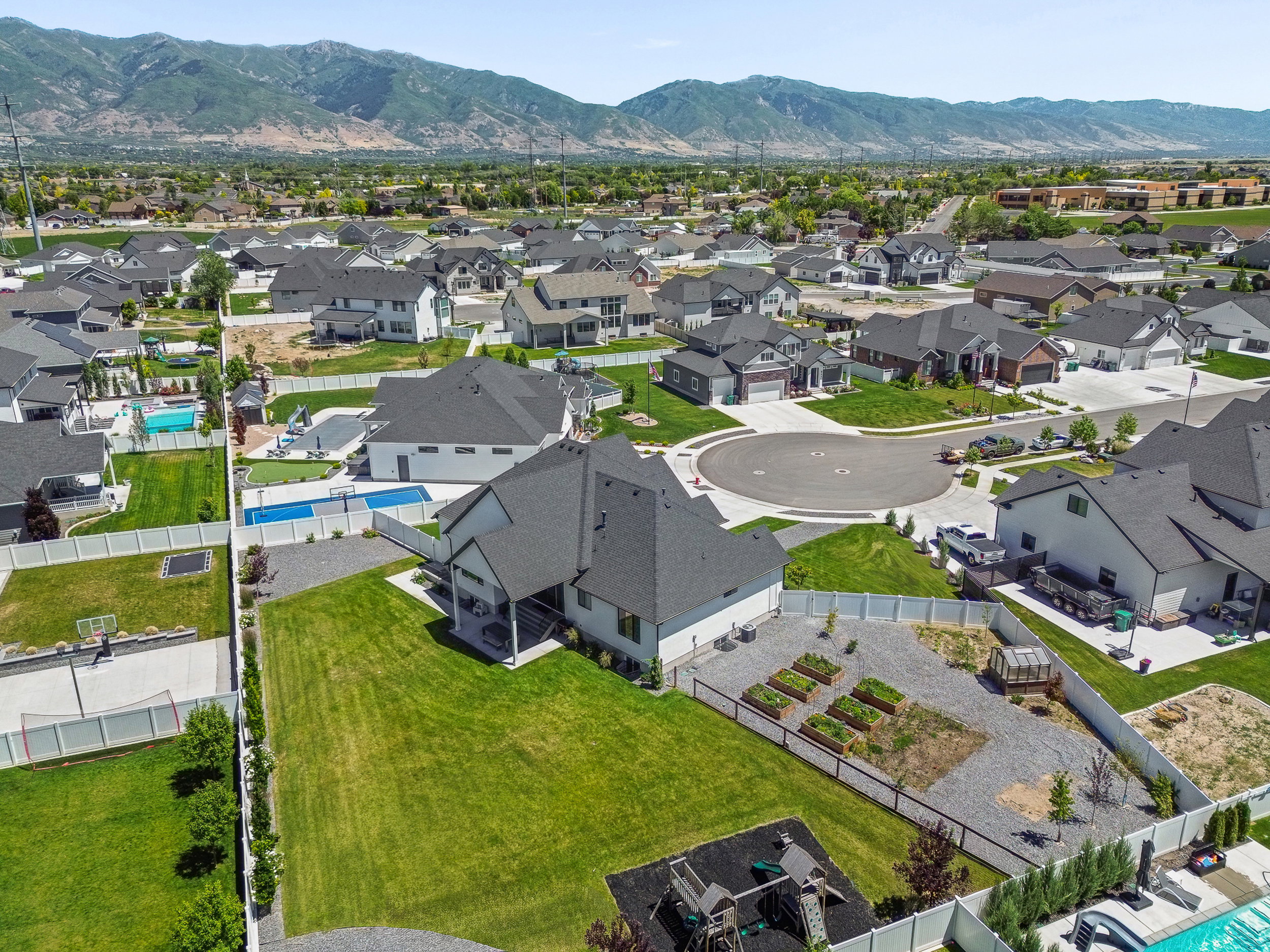 Expansive backyard featuring a lush lawn, dedicated garden beds, and mountain backdrop