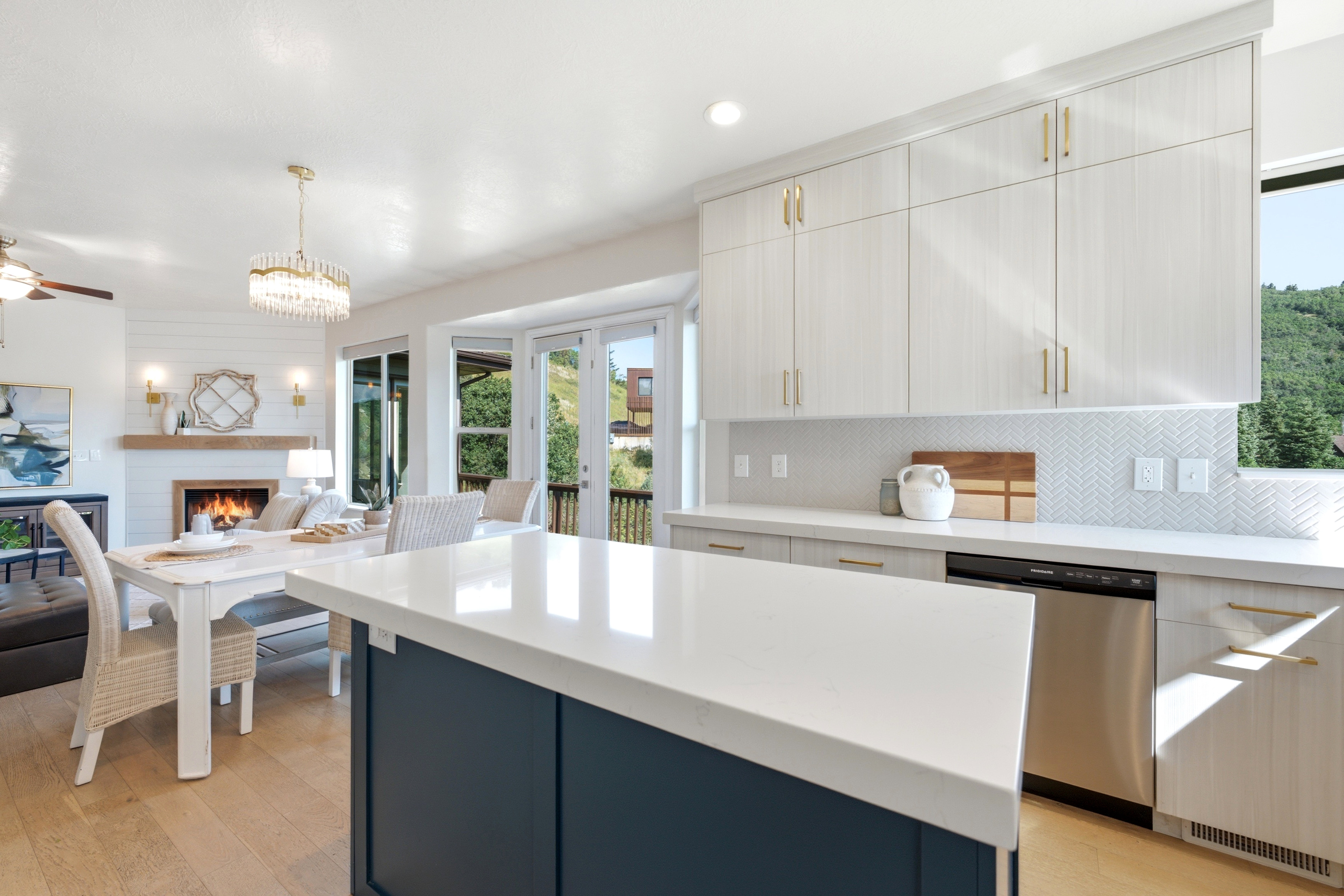 Kitchen island with a white countertop and blue base, featuring light wood-finish cabinetry with brass hardware