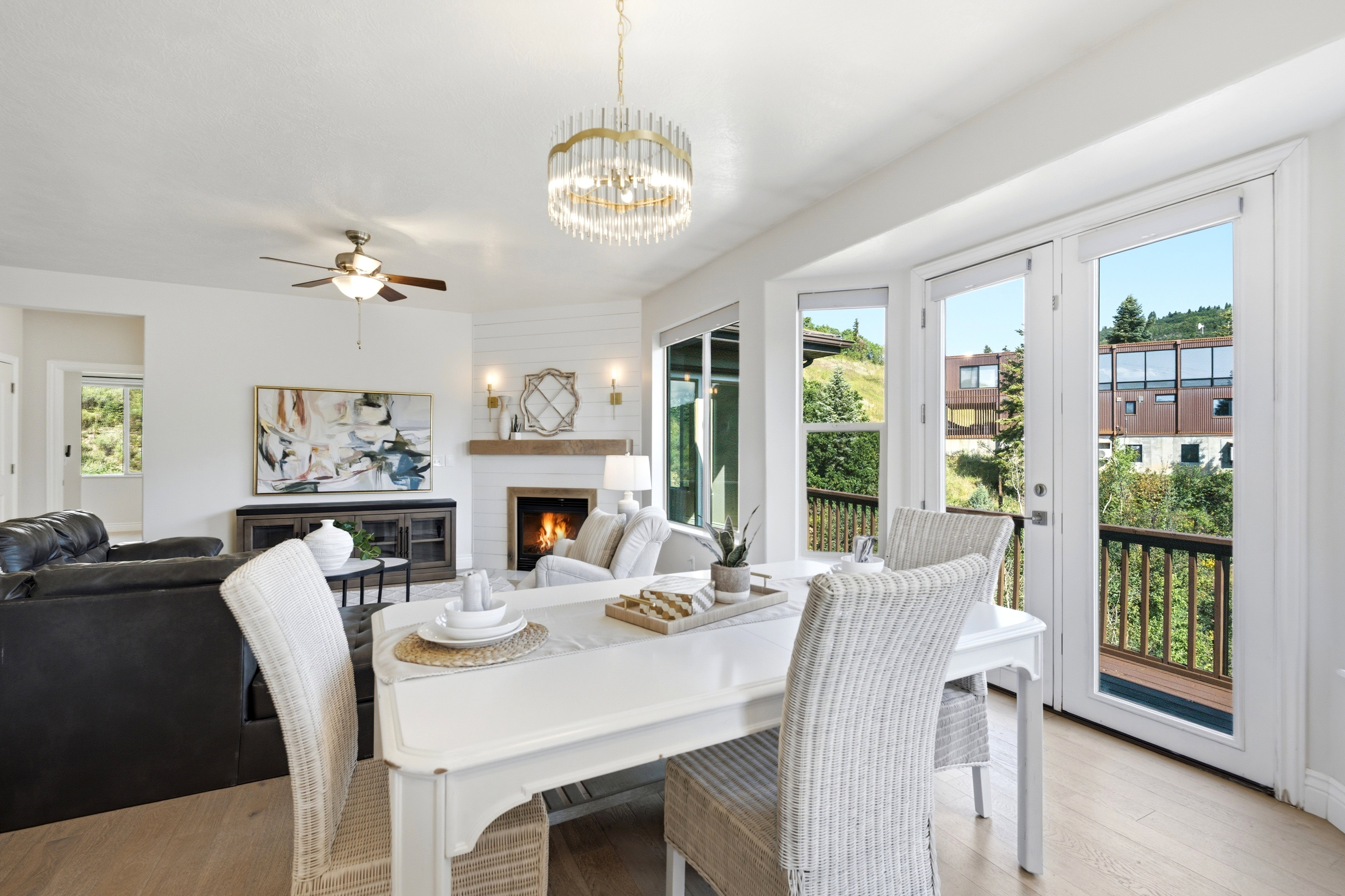 Bright dining area with wood-finish flooring, a contemporary chandelier, and French doors opening to an exterior balcony