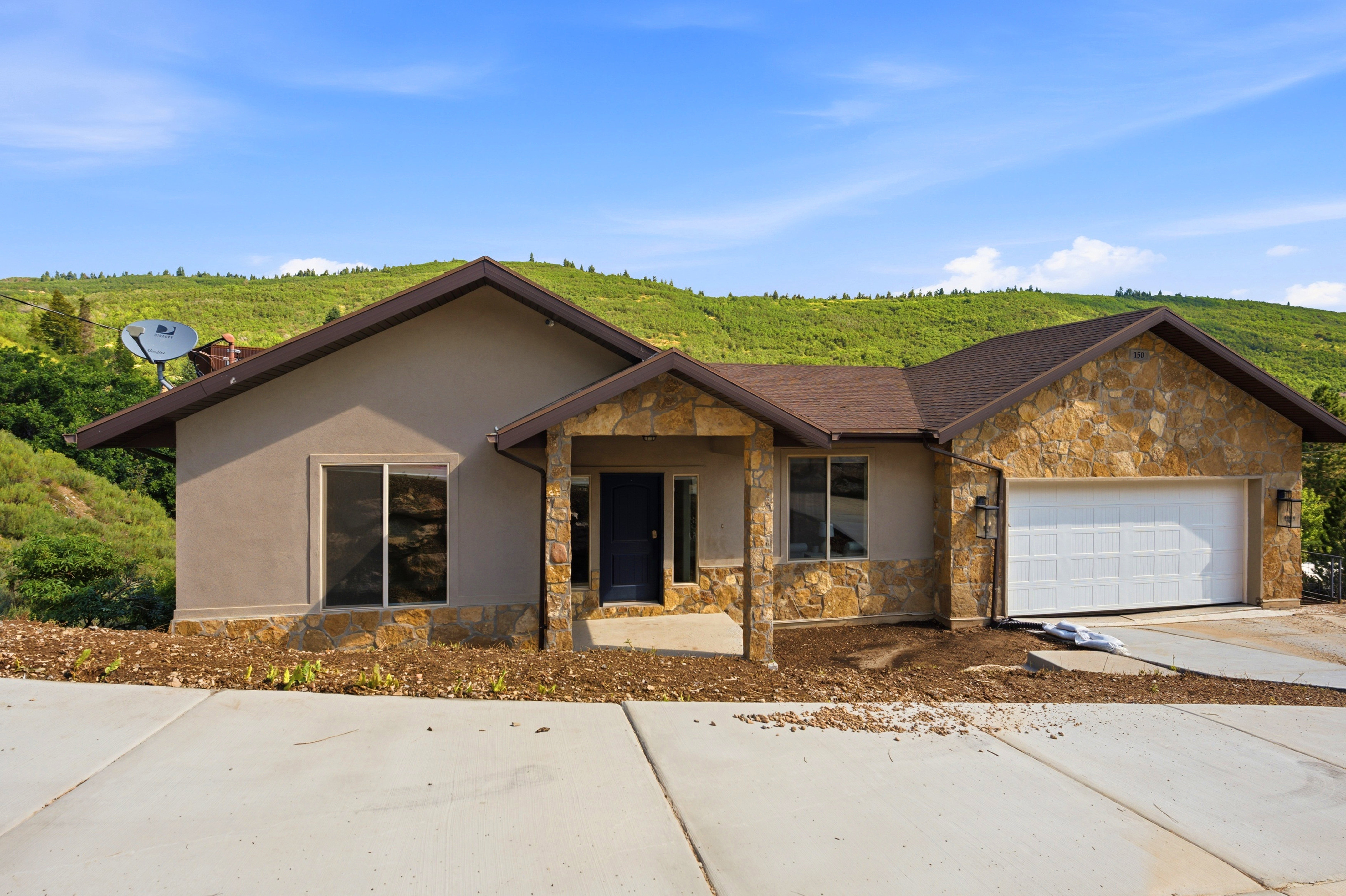 Stone and stucco exterior with a dark entry door and attached two-car garage