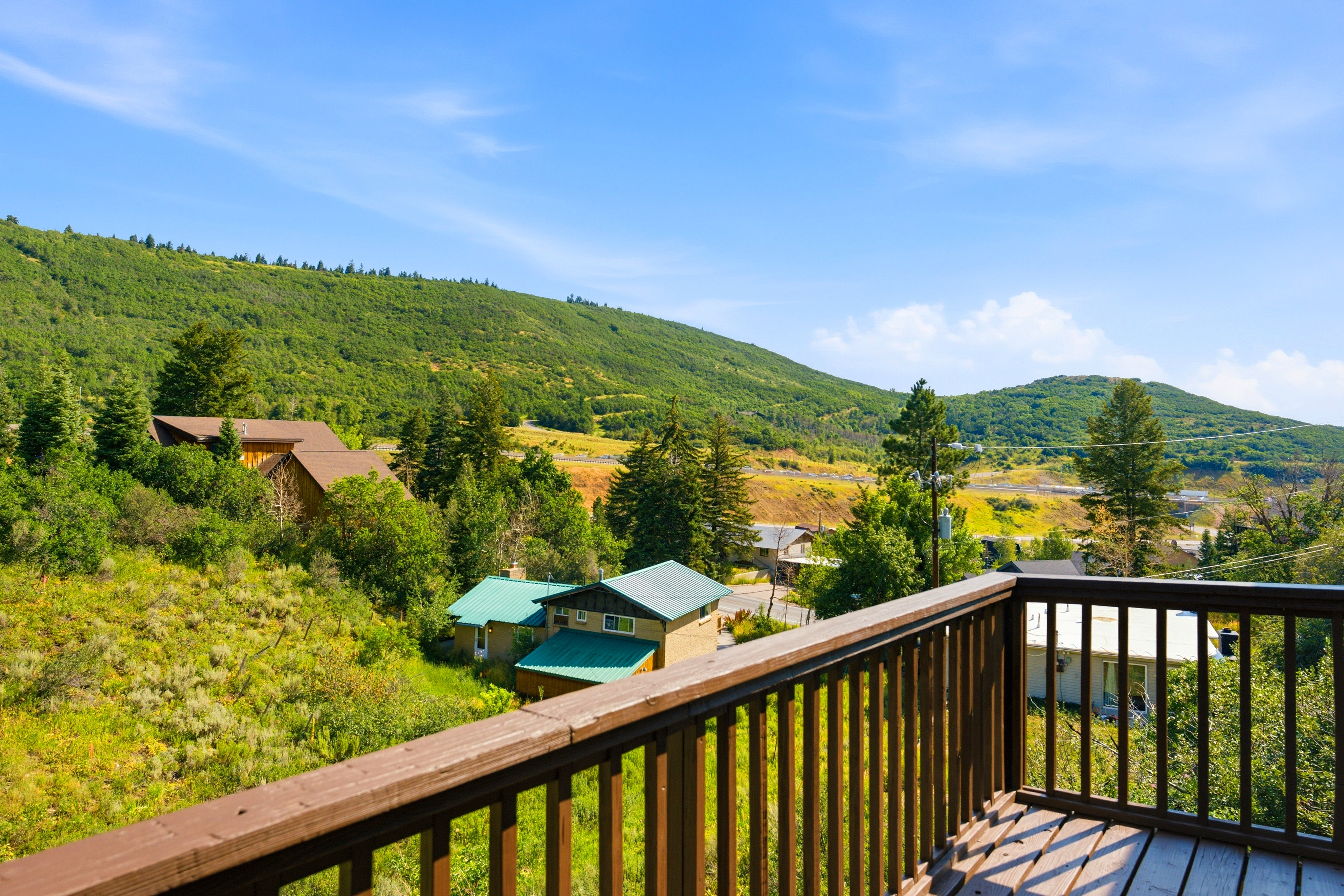 Outdoor deck with wood railings, offering expansive views of surrounding green hills and distant structures