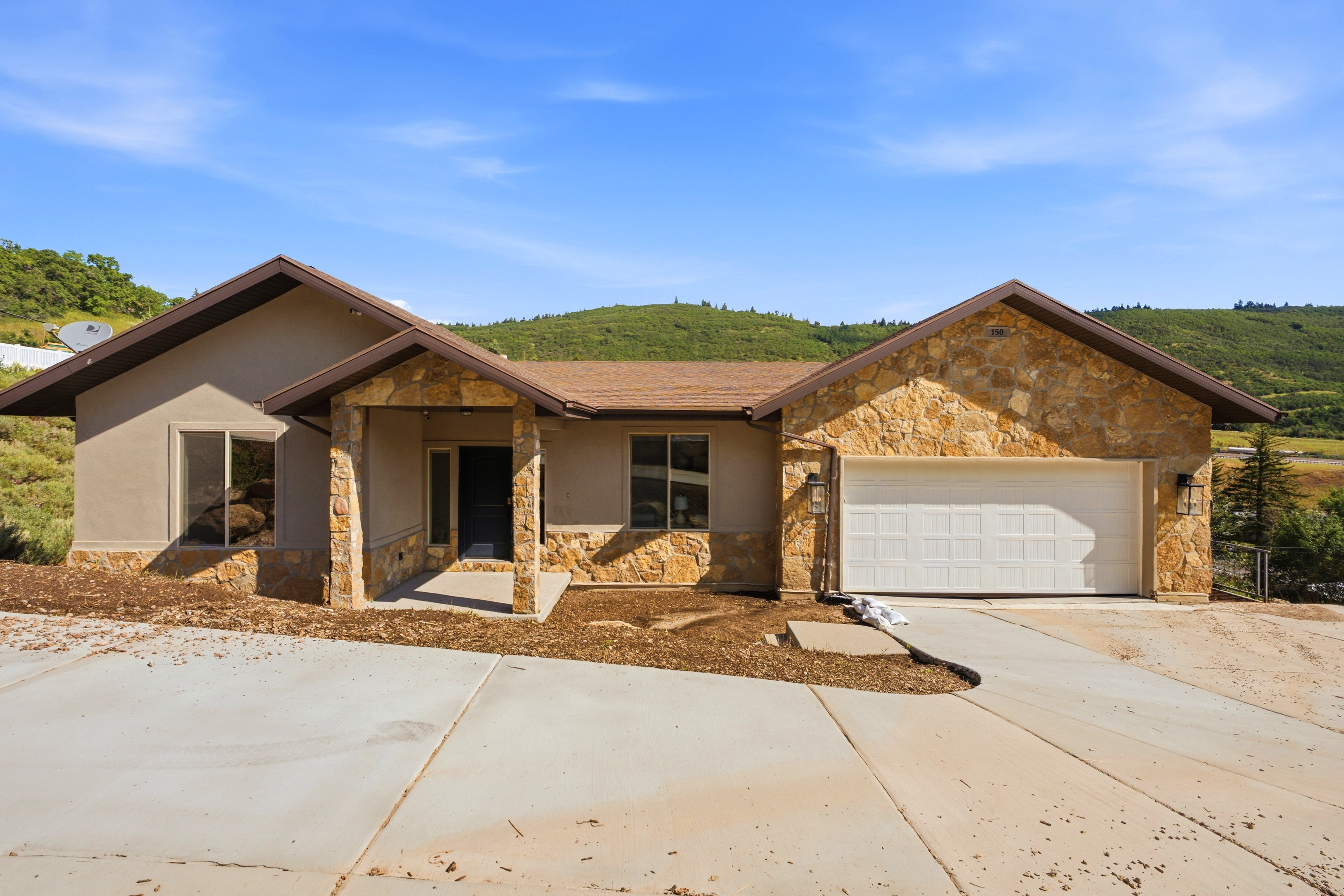 Single-story residence featuring a stone and stucco exterior, an attached two-car garage, and a covered front entry