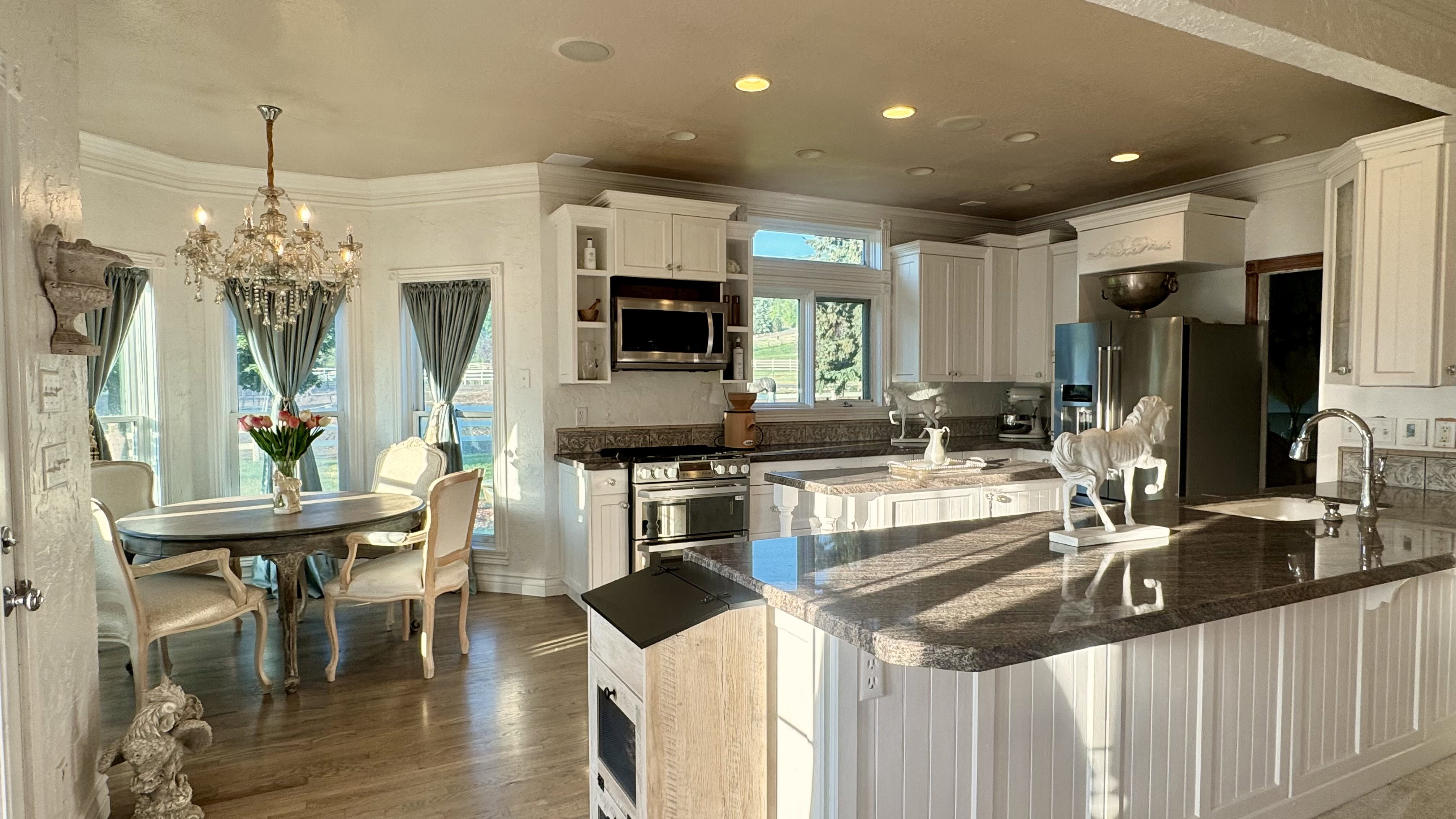 Gourmet kitchen with white cabinetry, stainless steel appliances, granite countertops, and a tiled backsplash