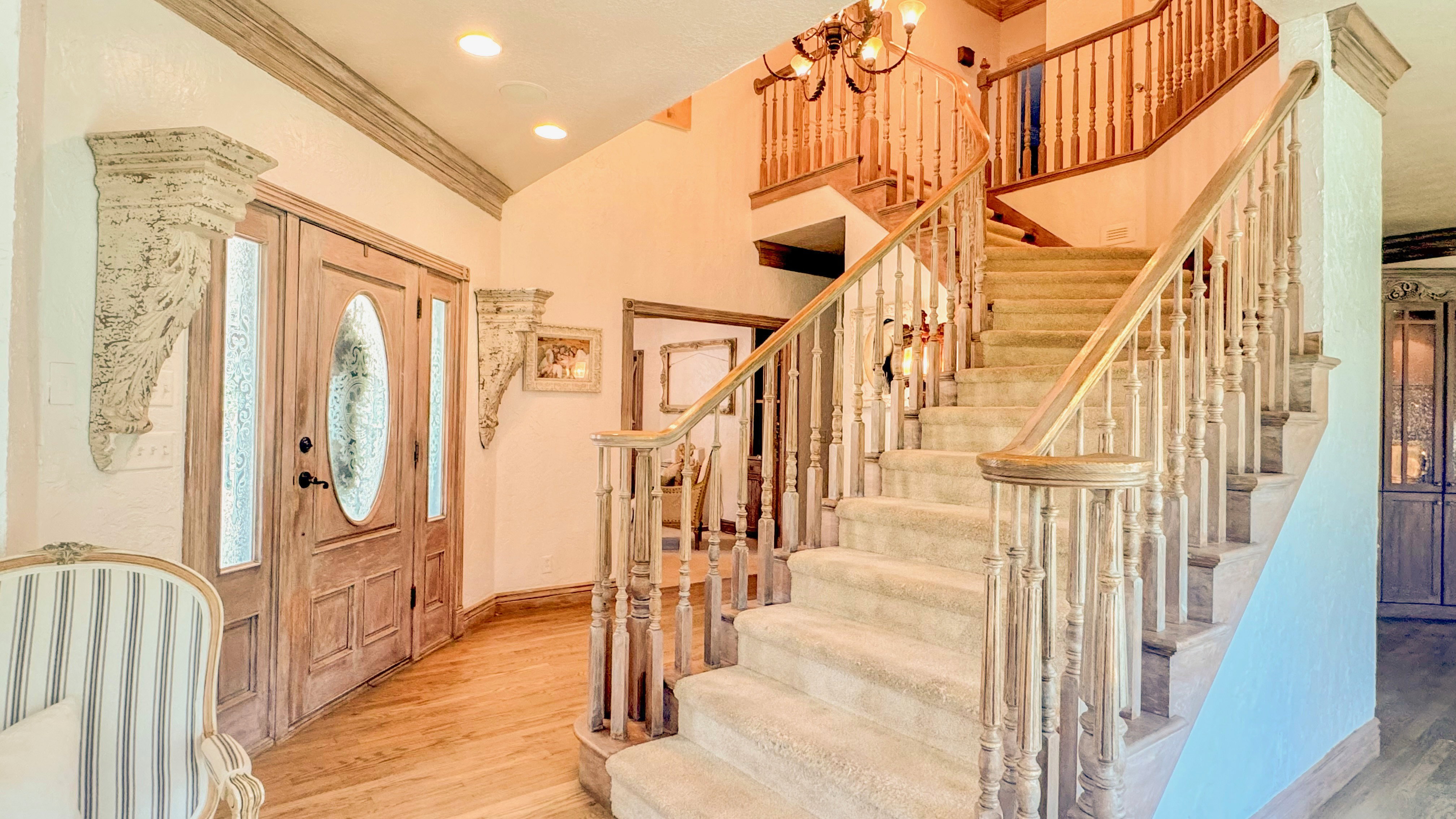 Gracious entry featuring a grand staircase with wood balusters, carpeted treads, and a wood handrail