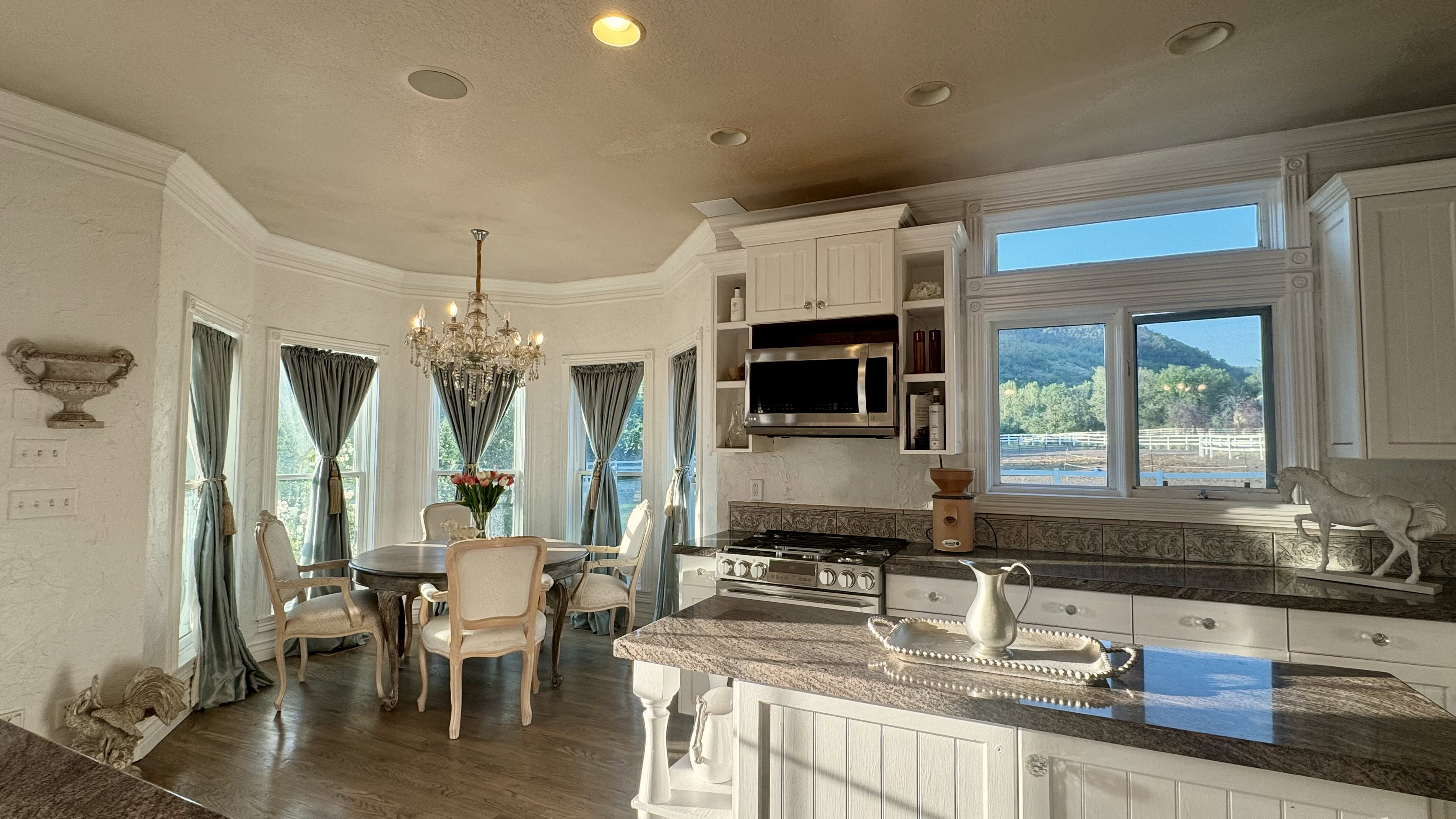 Integrated kitchen and dining area featuring a bay window with a crystal chandelier