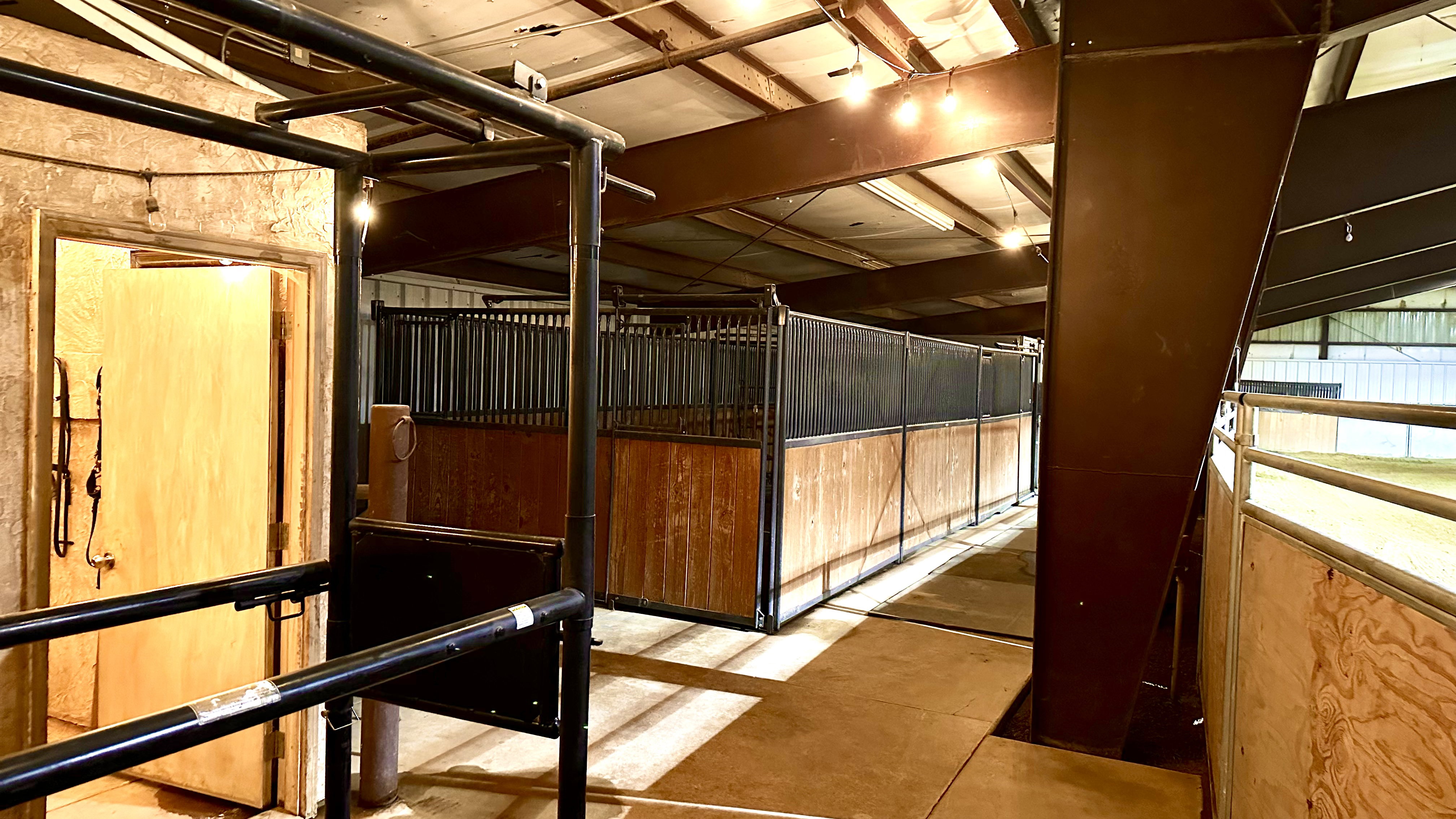 Interior barn stalls featuring wood-finish walls and black metal grating