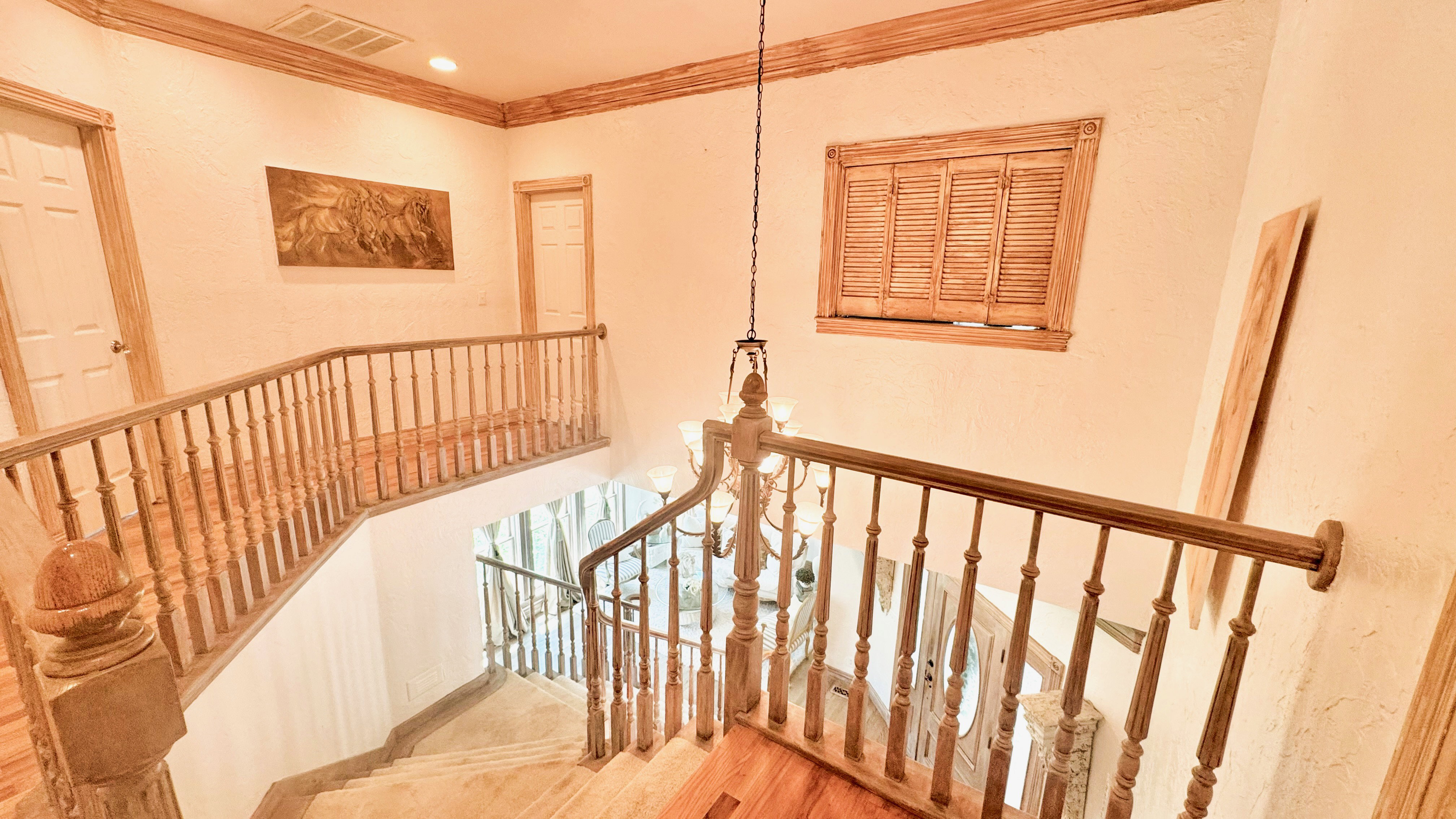 Multi-level staircase featuring light wood-finish flooring, wood balusters, and a matching wood handrail