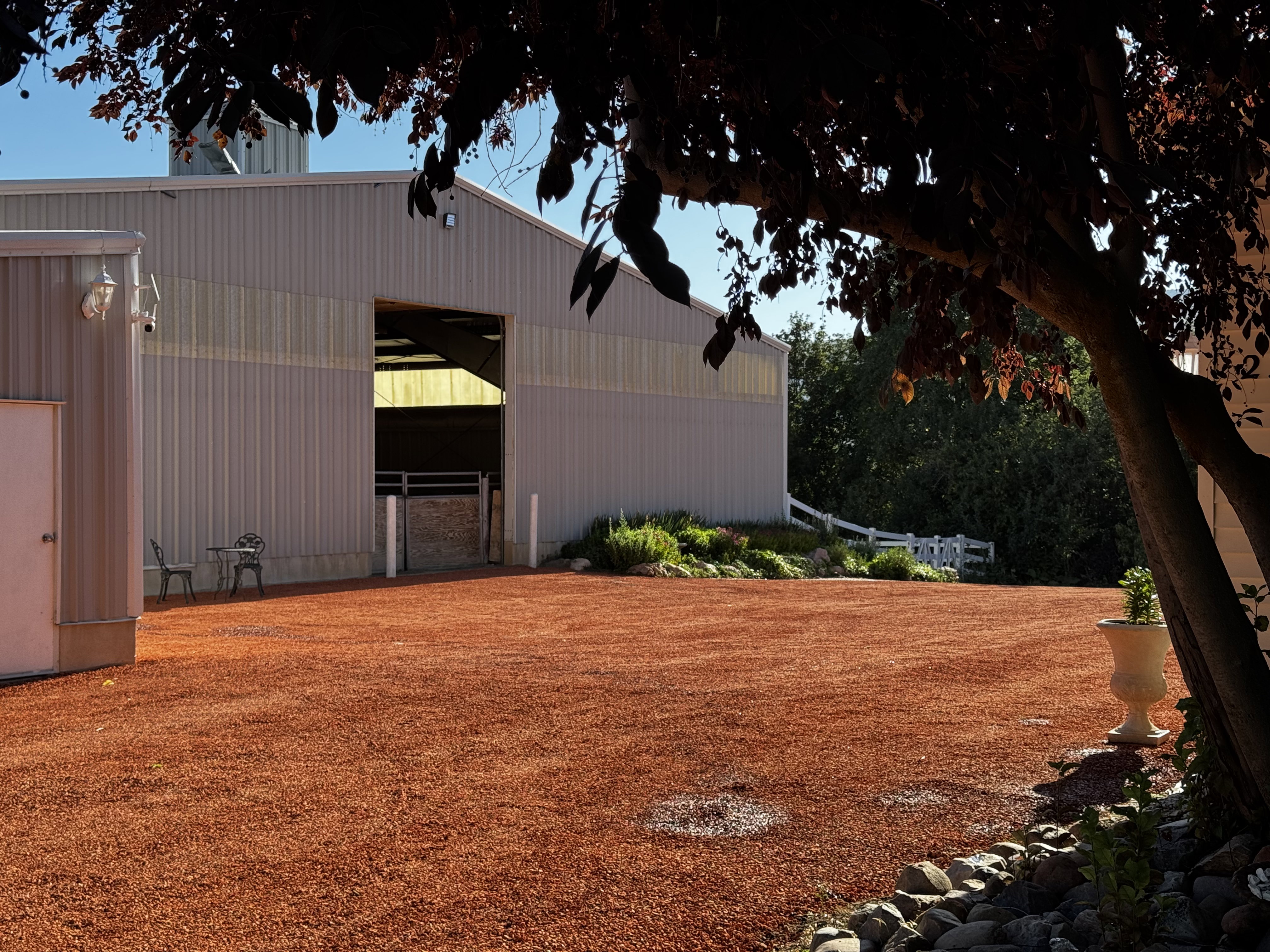 Expansive red gravel area fronting a large utility building with a prominent open bay entrance
