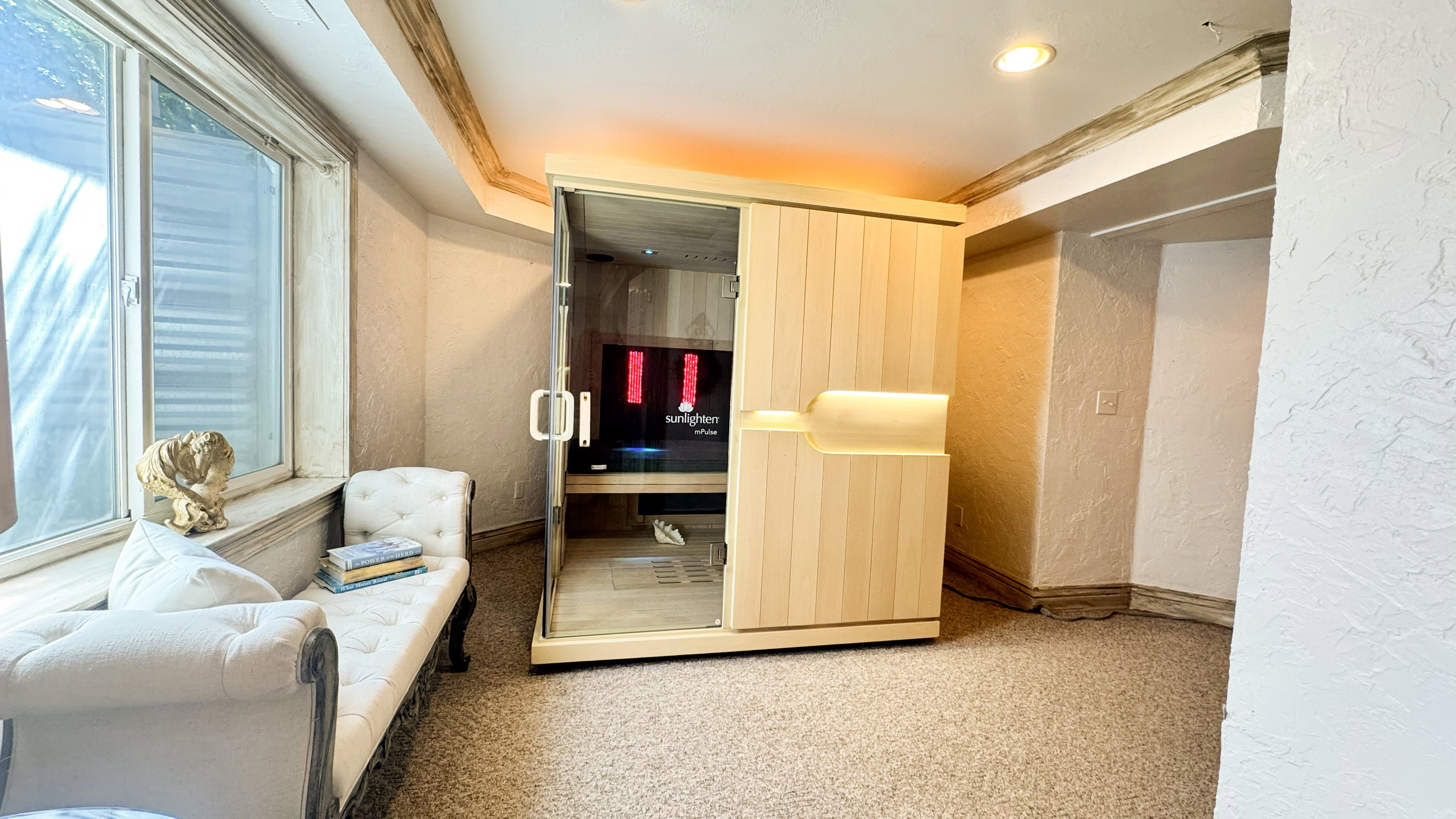 Dedicated wellness space featuring a modern light wood sauna with a glass entry, recessed lighting, and a textured wall finish