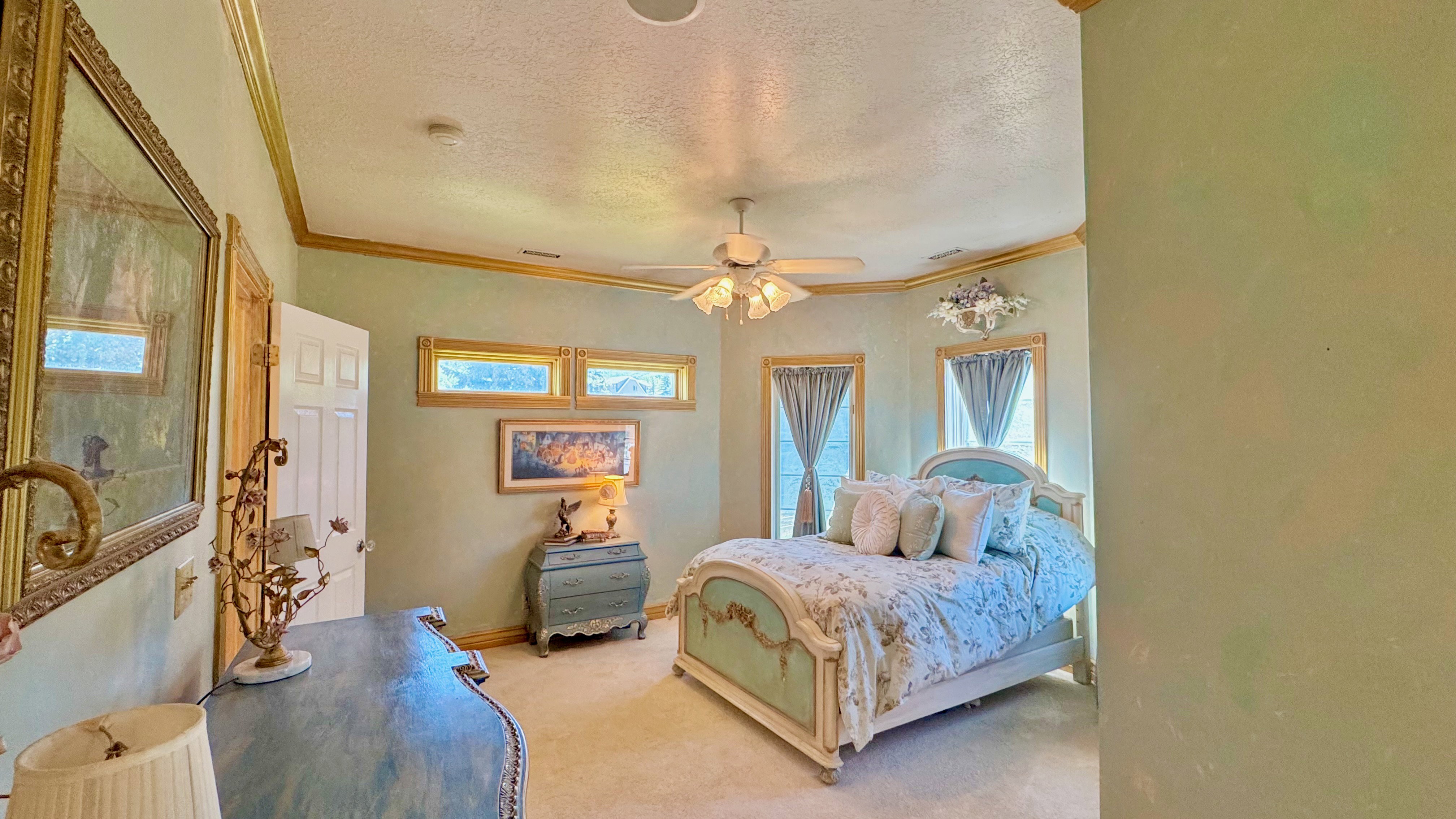 Recessed lighting and a ceiling fan fixture highlight a room featuring a paneled door, three transom windows, and two full-height windows with architectural trim