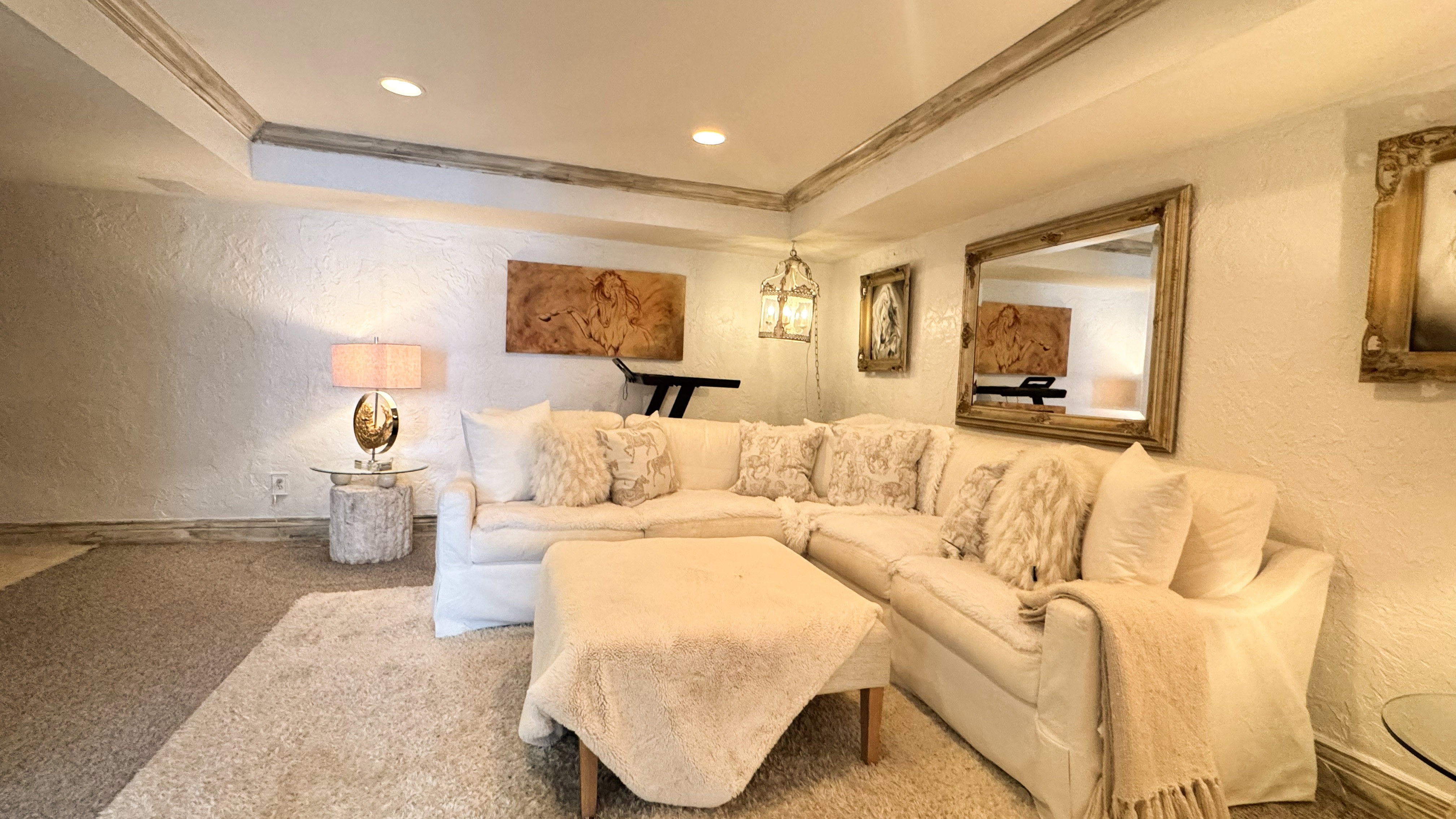 Recessed lighting illuminates a carpeted living space with textured walls and ceiling beams